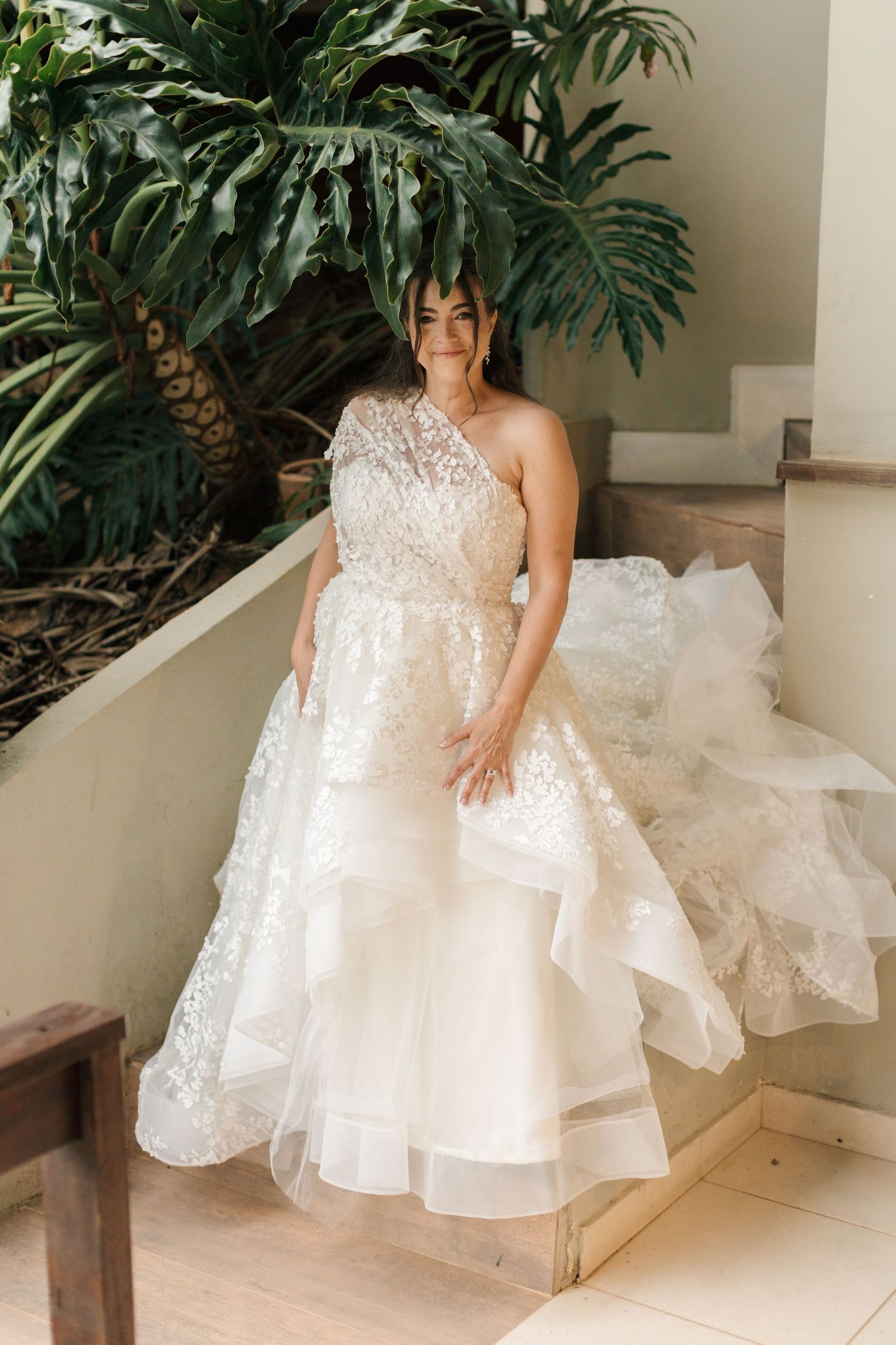 Elegant white wedding gown with layered tulle skirt displayed on outdoor steps.