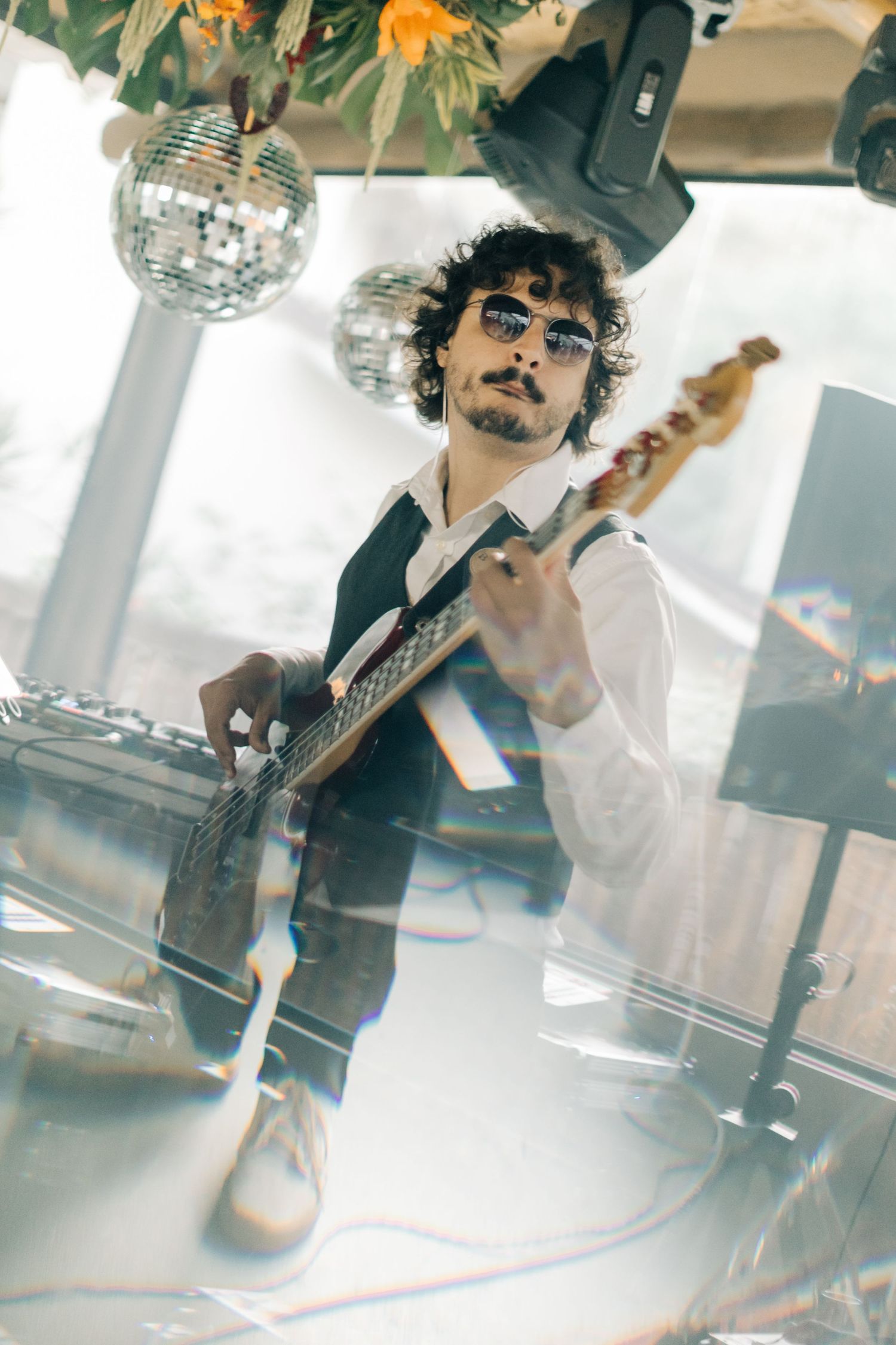 Guitarist performing on stage with a disco ball in a dreamy atmospheric setting.