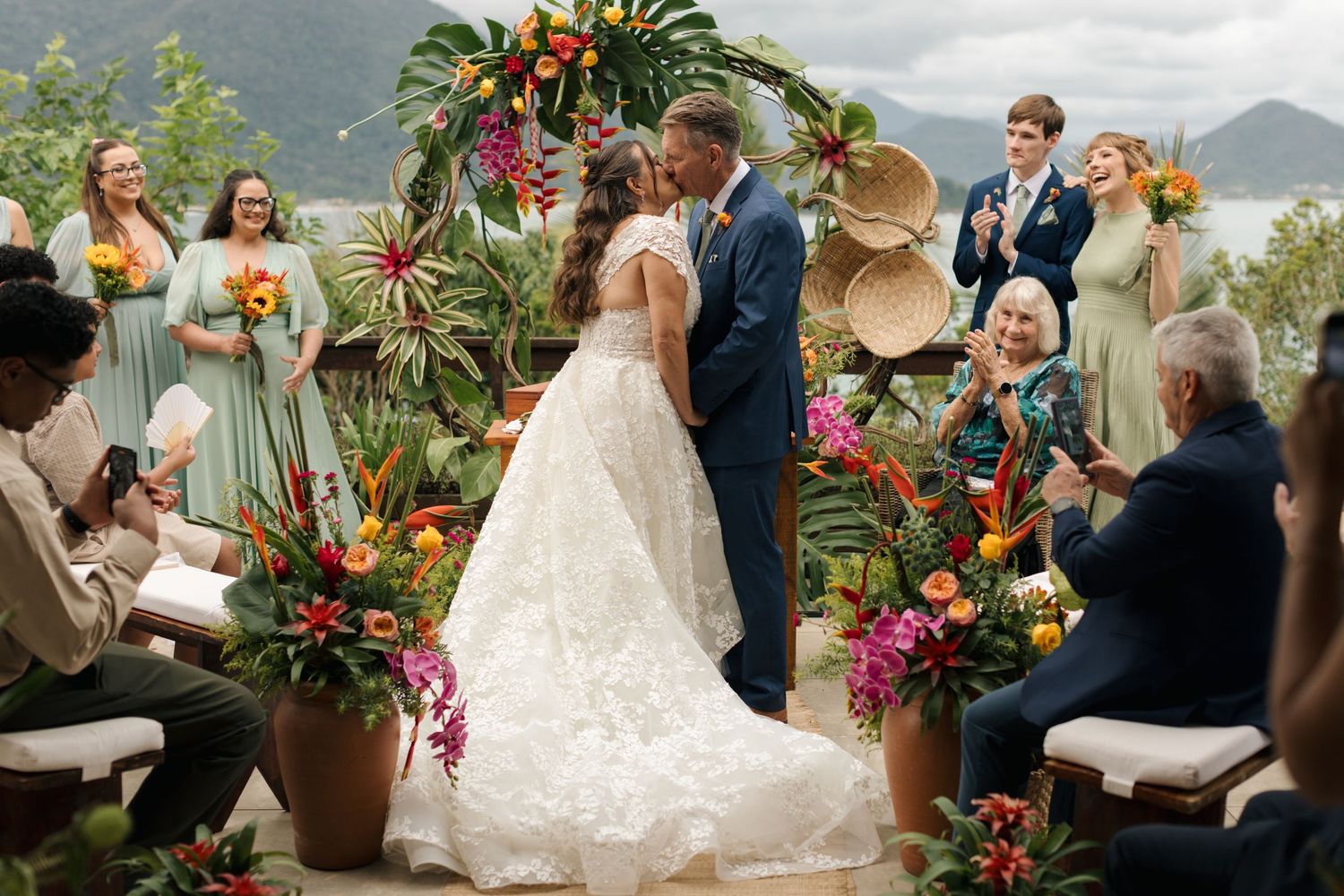 Tropical-themed wedding ceremony setup with colorful floral arrangements and mountain views.
