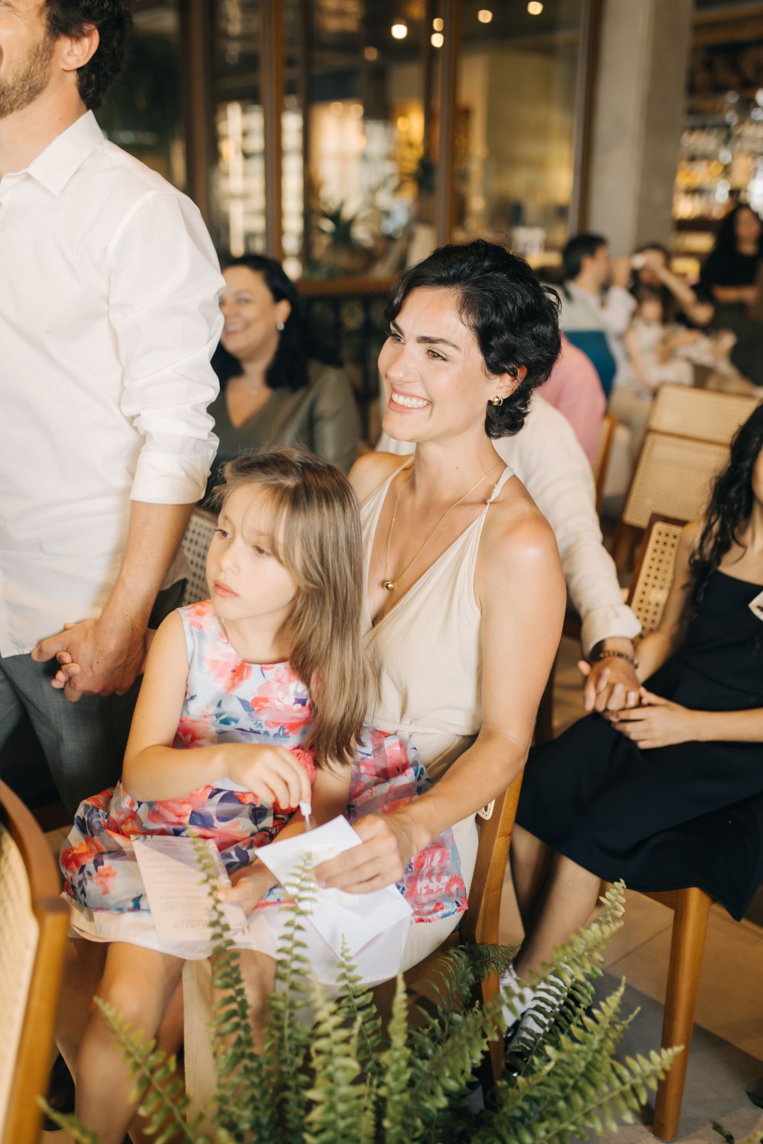 Wedding guests seated at tables with fern decorations enjoying a celebratory moment.