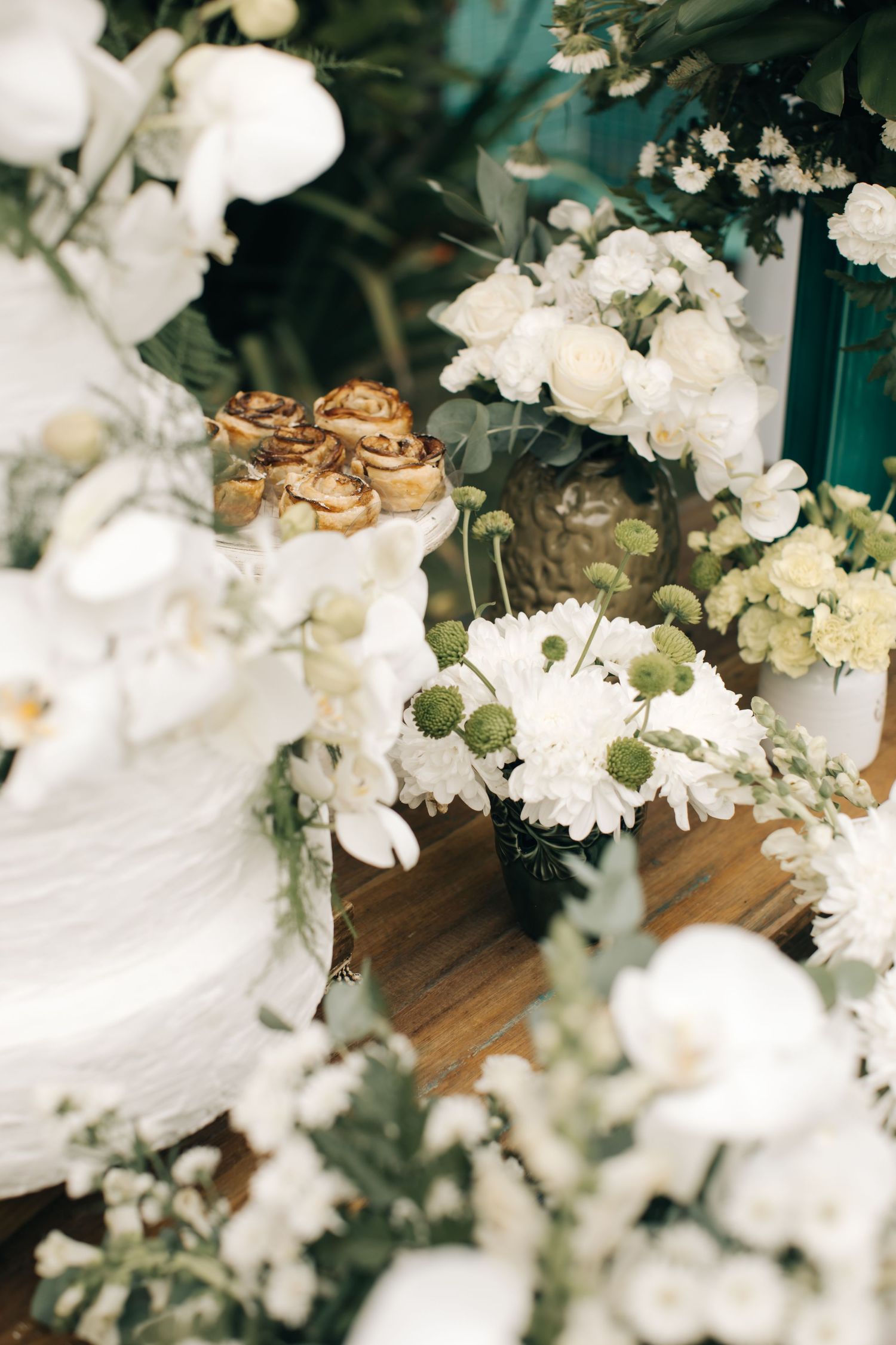 Elegant floral arrangement with white flowers and gold accents on a wooden surface.