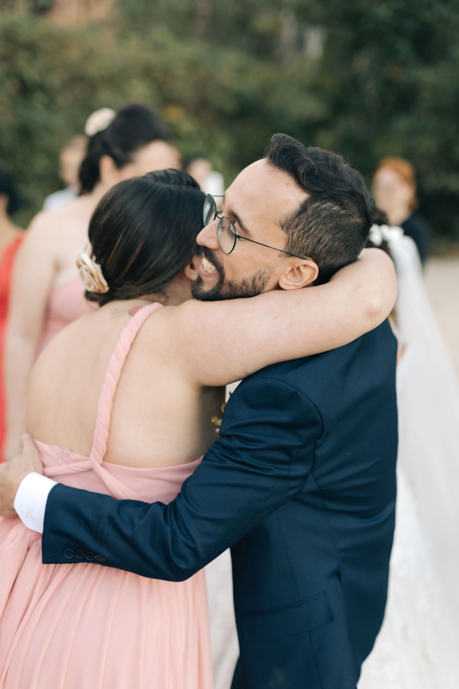 Wedding guests share warm hug during outdoor celebration.
