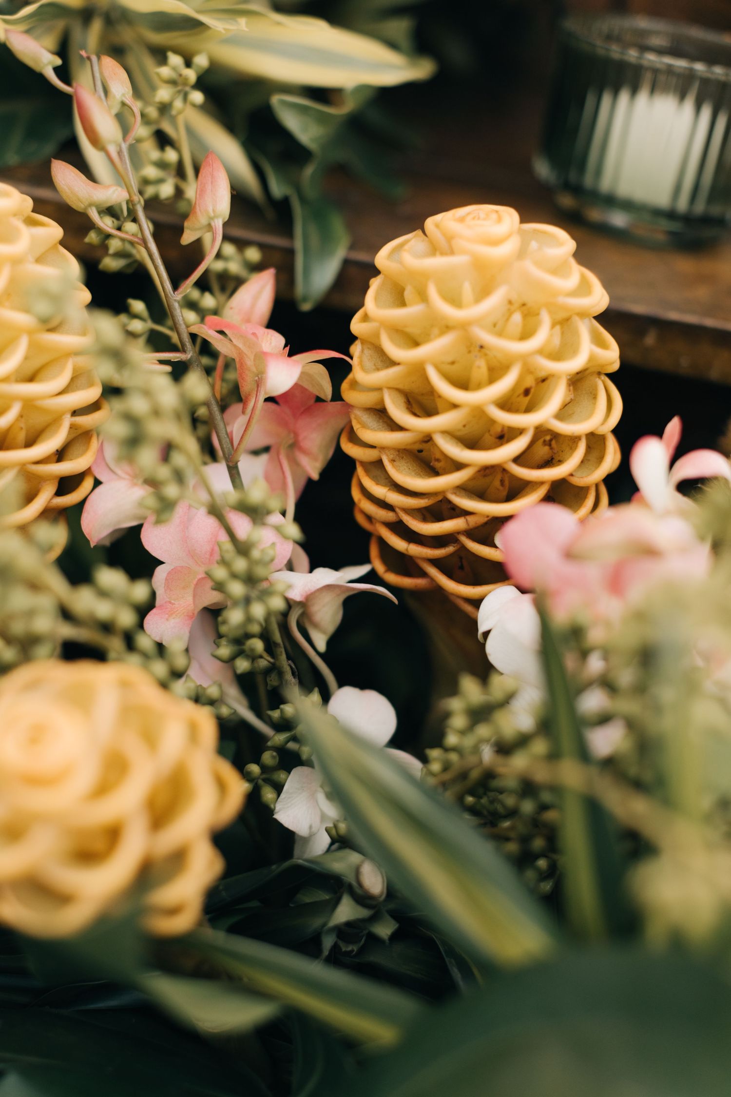 Delicate floral arrangement with yellow roses and pink blossoms in soft focus.