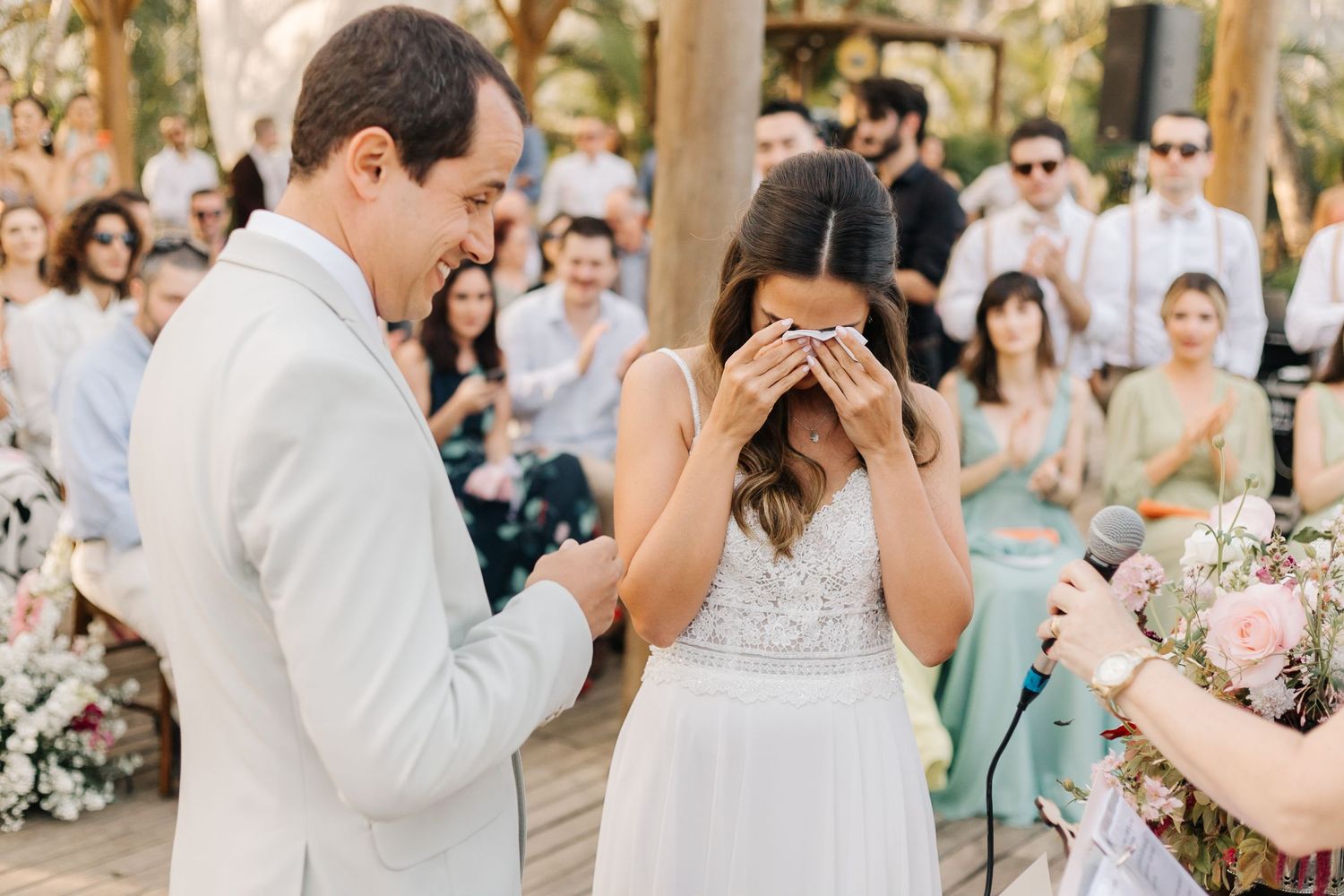 Joyful wedding celebration under wooden beams with pink floral arrangements.
