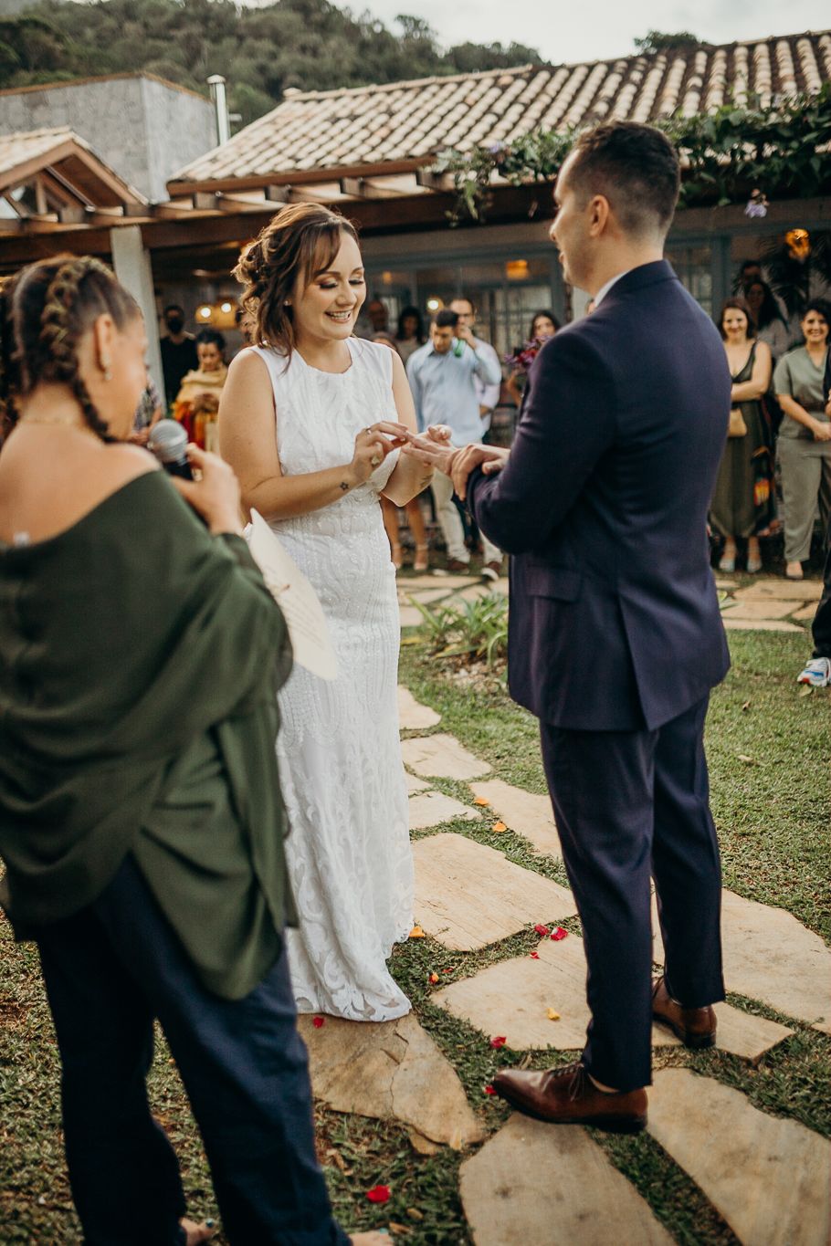 A couple shares an intimate moment during their wedding ceremony on a stone pathway with guests watching.