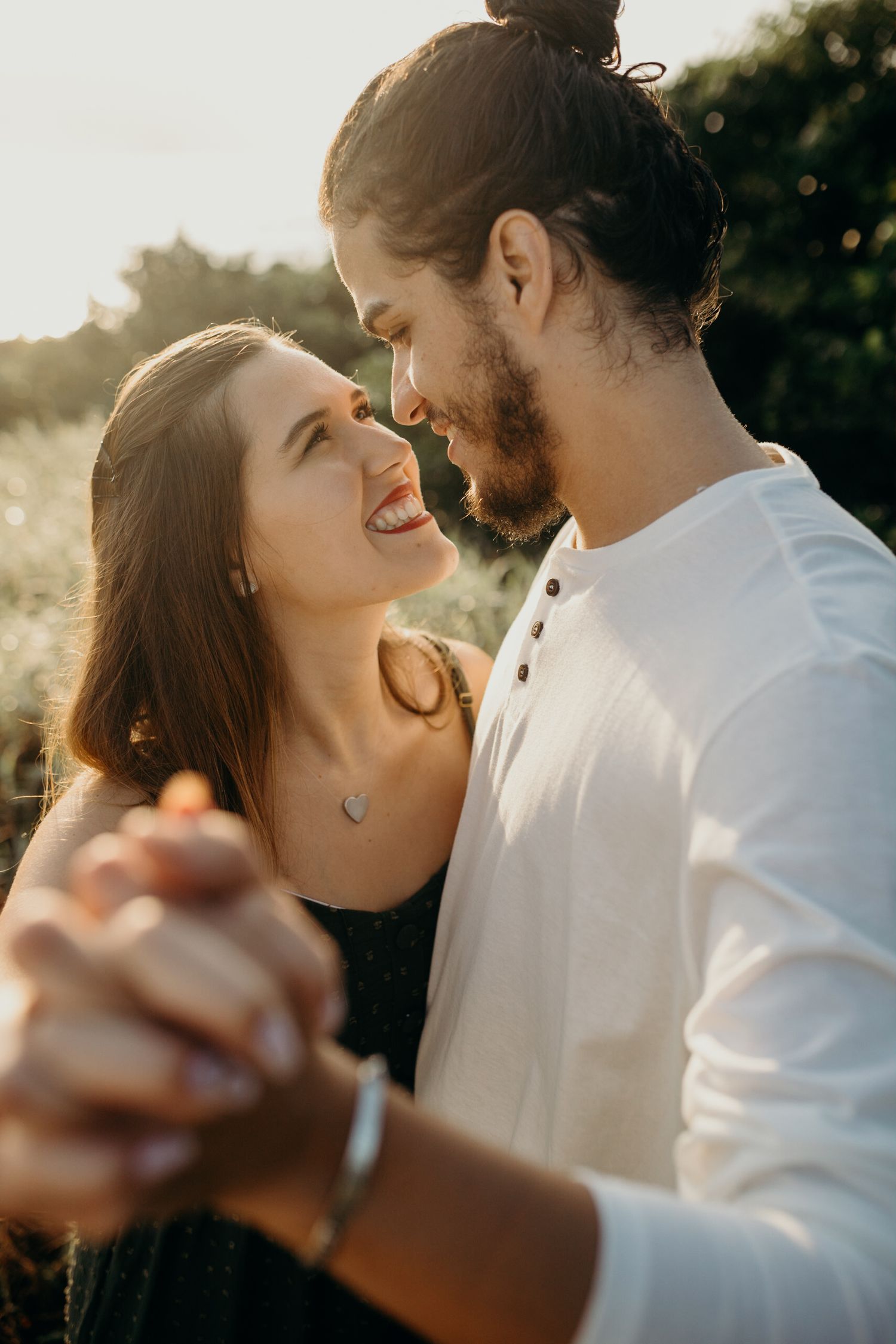 Joyful couple dancing together during sunset engagement session.