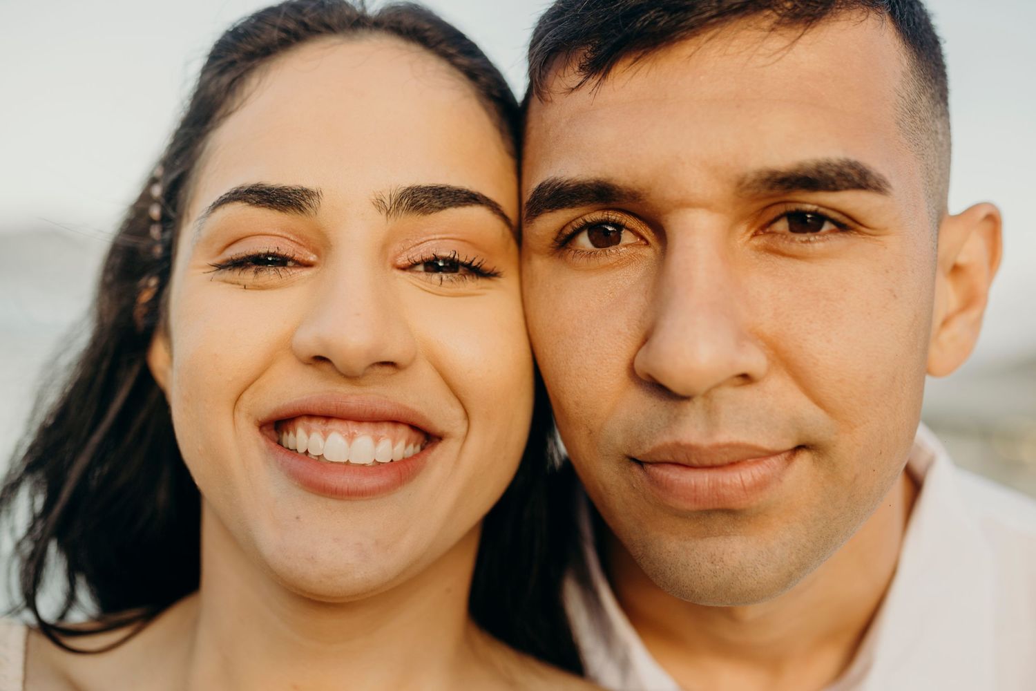 Happy couple poses for a bright, close-up portrait together.