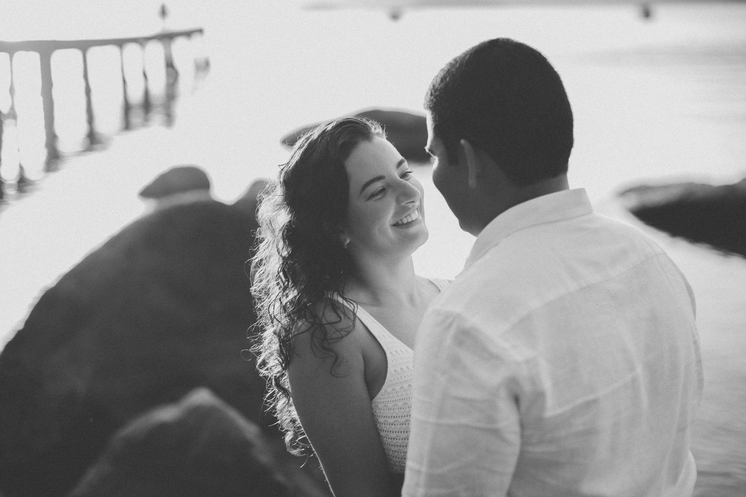 A candid black and white moment of laughter and joy during a seaside photoshoot.