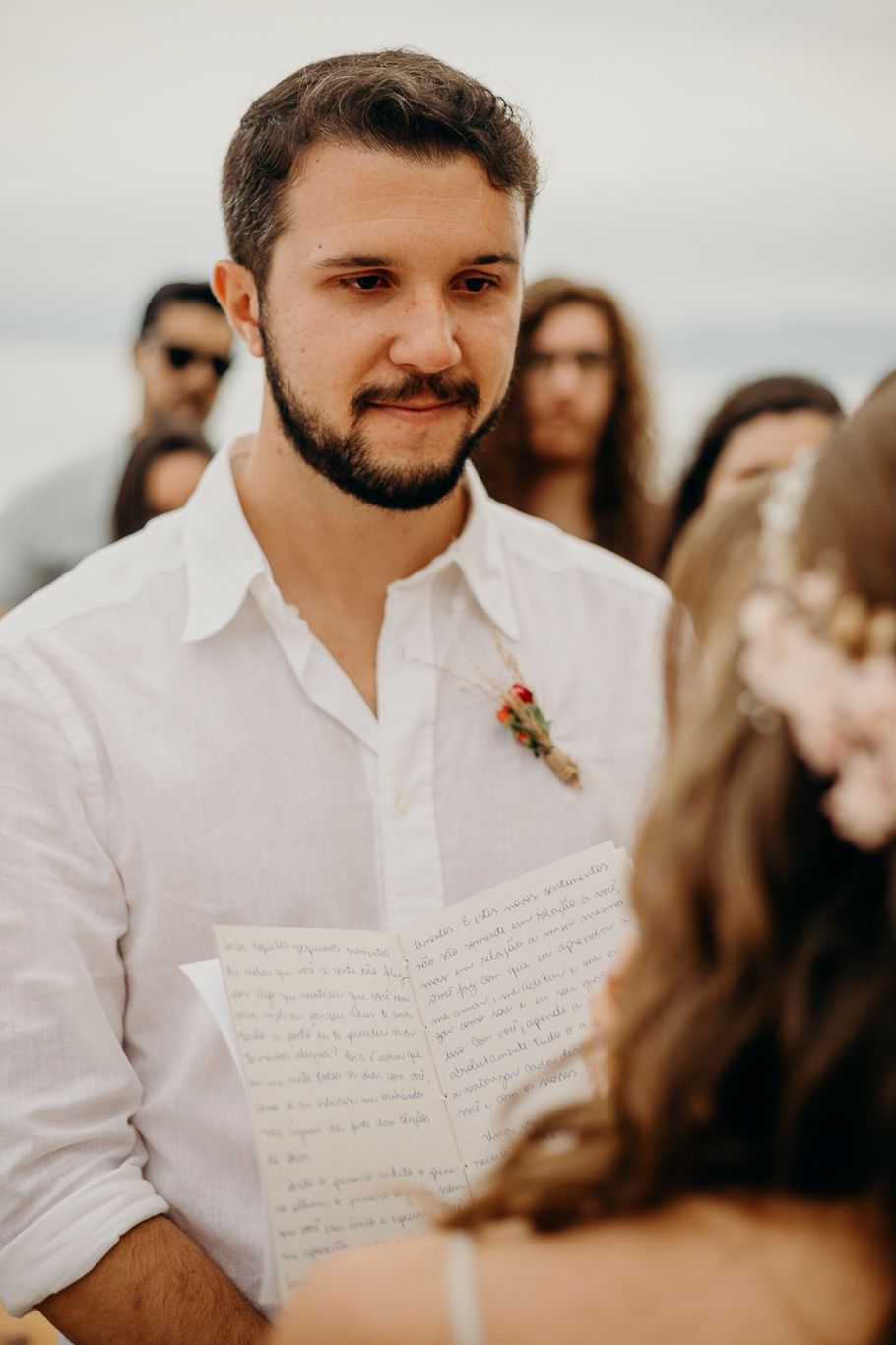 Wedding ceremony participant holds handwritten vows during outdoor celebration.