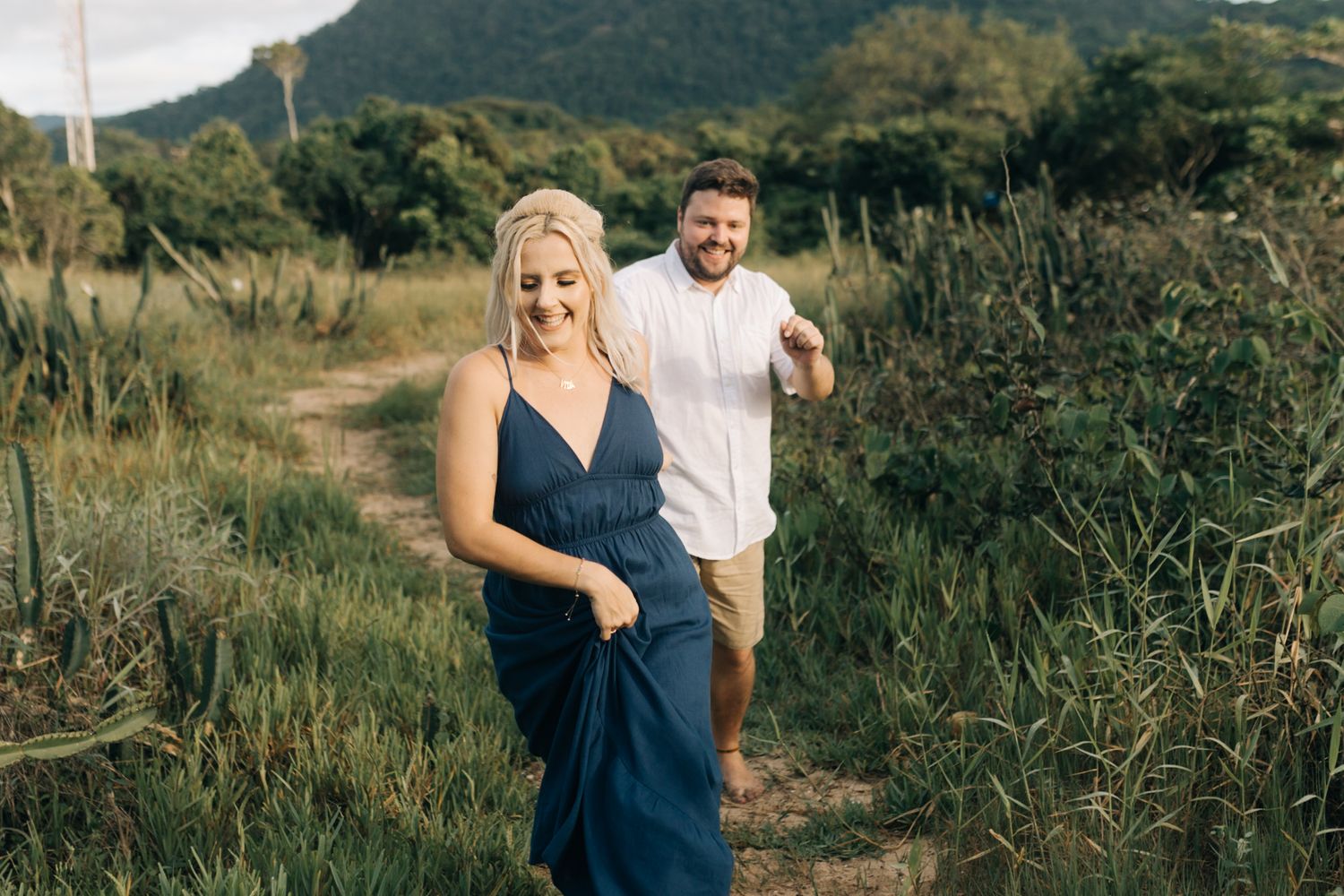 Joyful interaction between two people on a scenic coastal hiking trail.