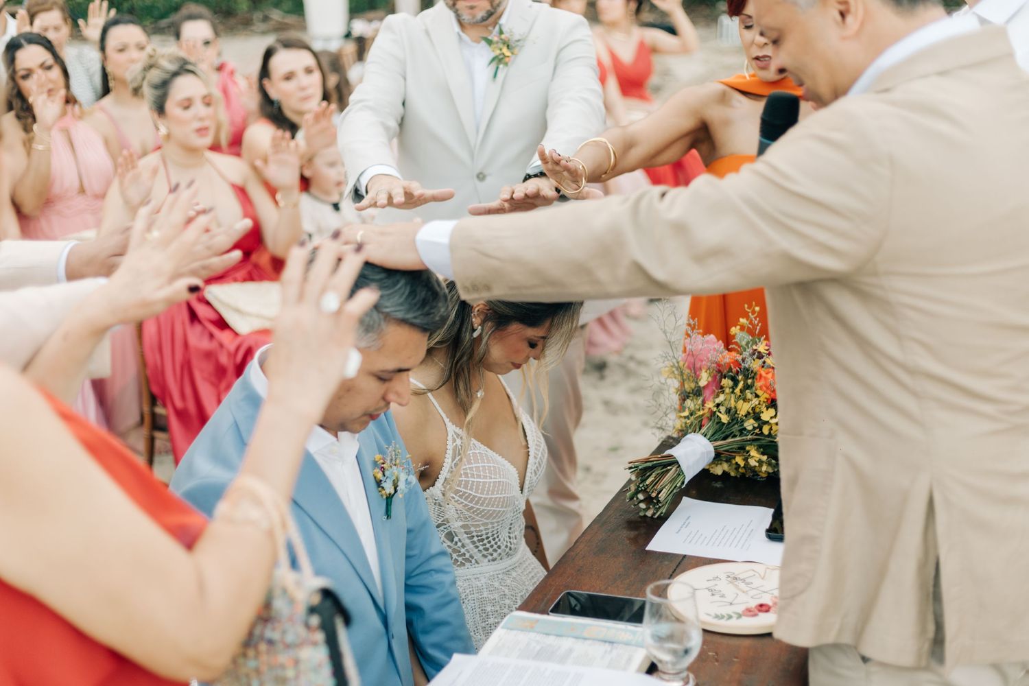 Wedding celebration moment captured on a beach with guests in formal attire.