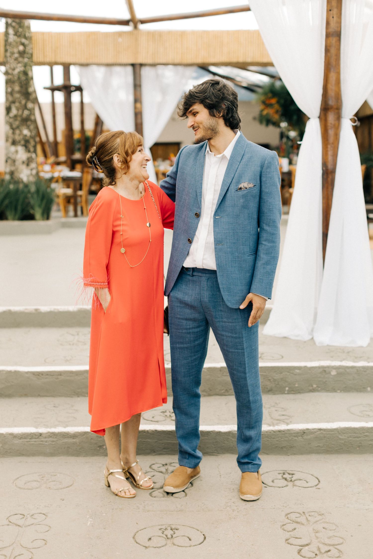 An outdoor portrait of two people in contrasting coral dress and blue suit.