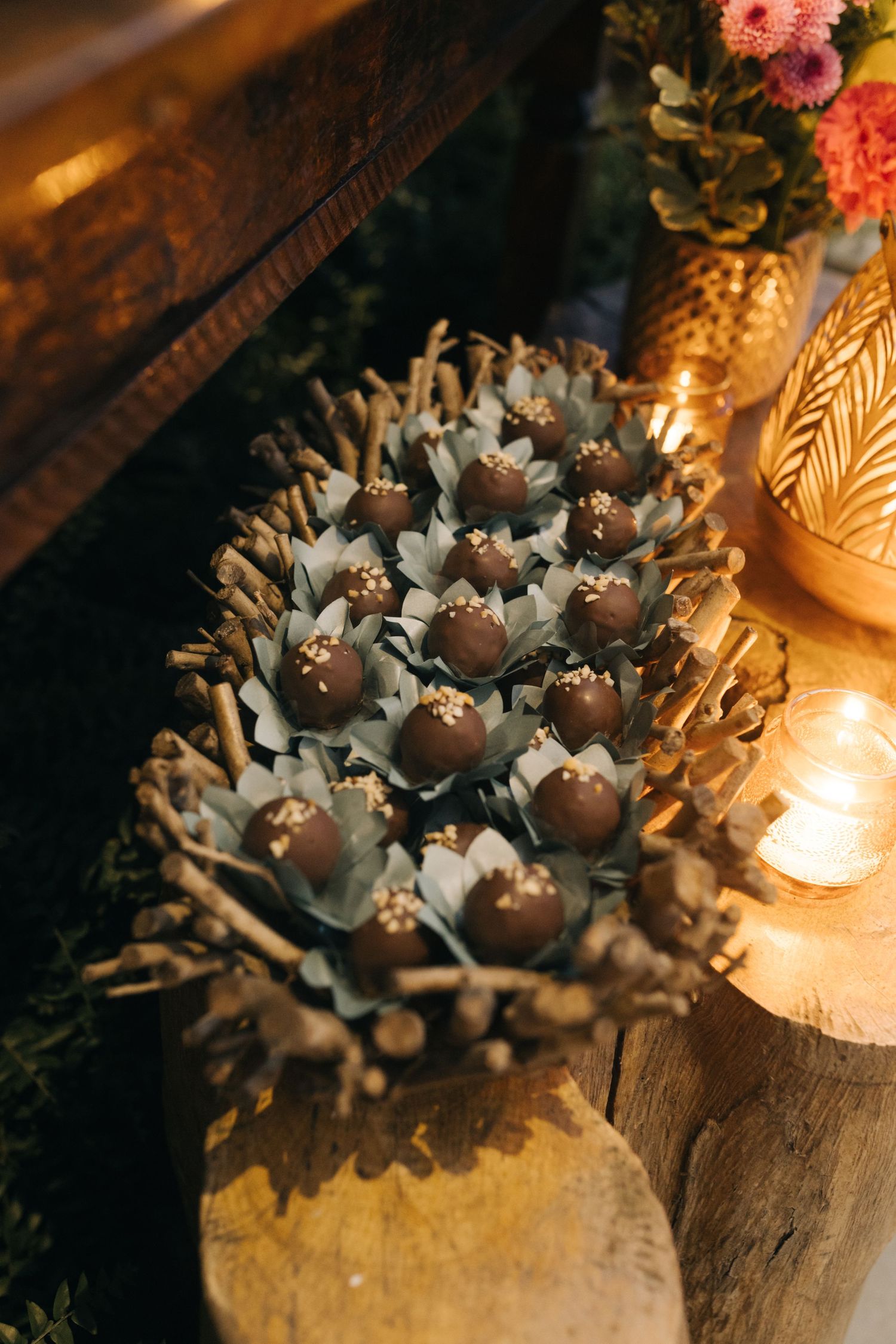 Artistically plated wedding desserts arranged on decorative paper with candlelight ambiance.