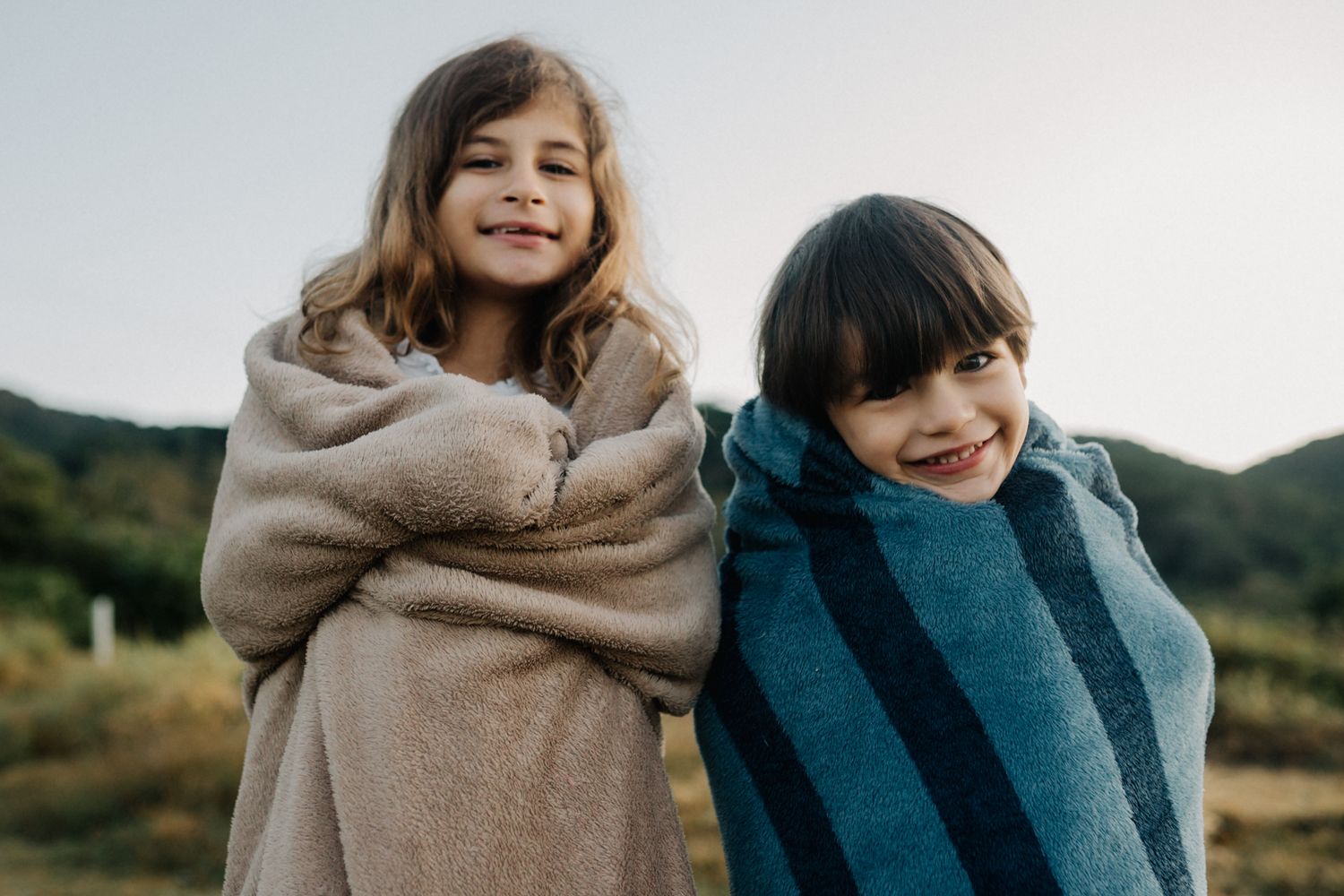 A playful family outdoor photo session in casual clothing against a natural landscape.
