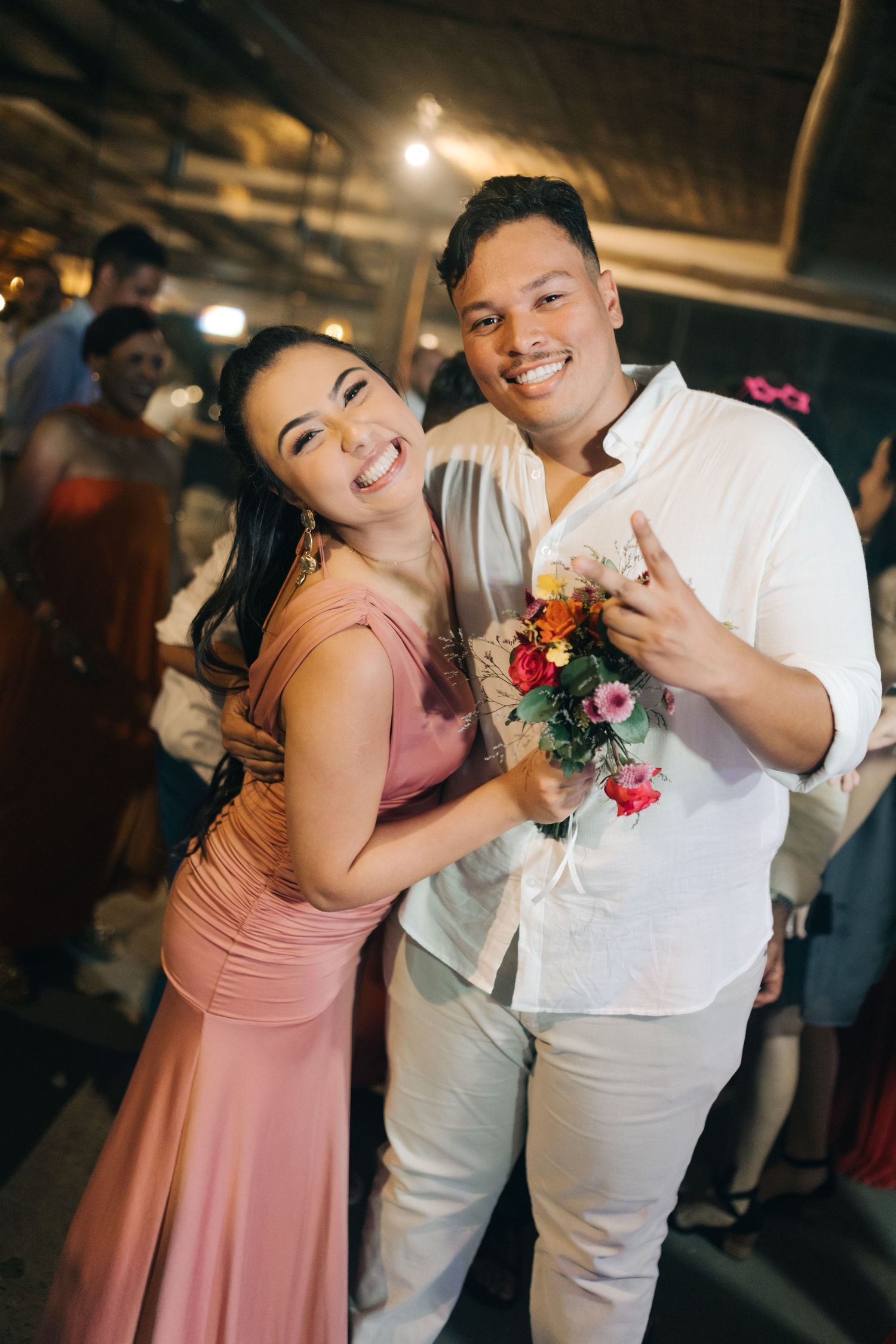 Wedding guests in formal attire pose with floral corsage at evening reception.