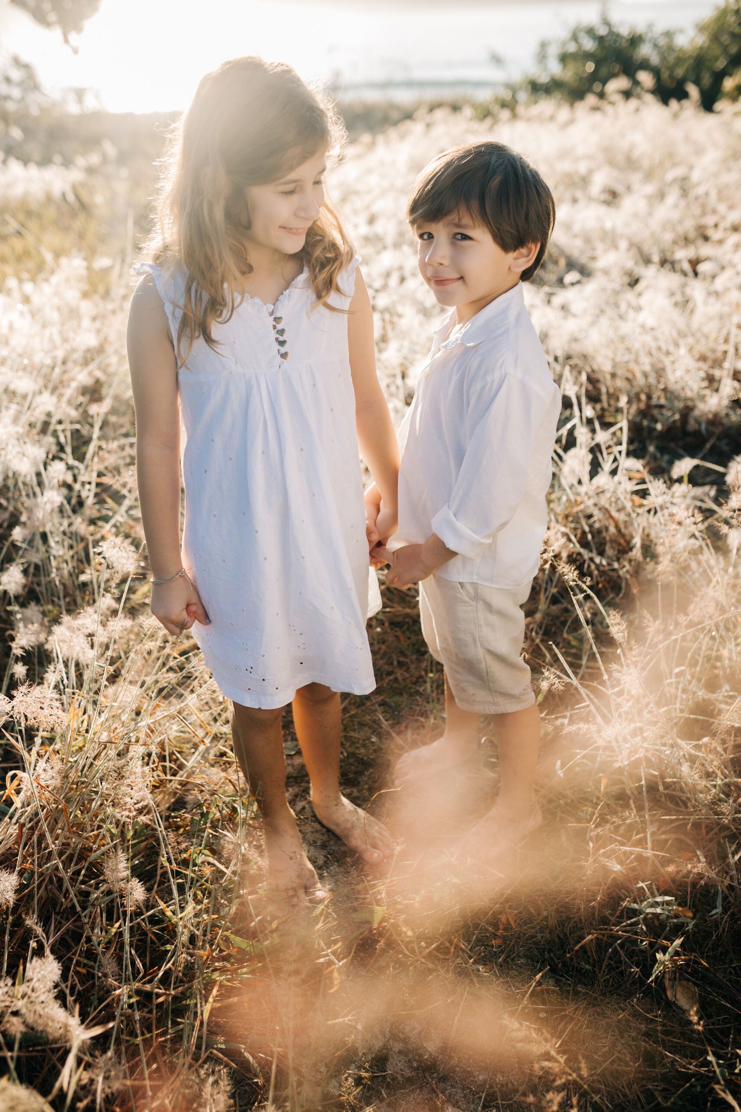 Two children share a sweet moment together in a sun-drenched meadow.