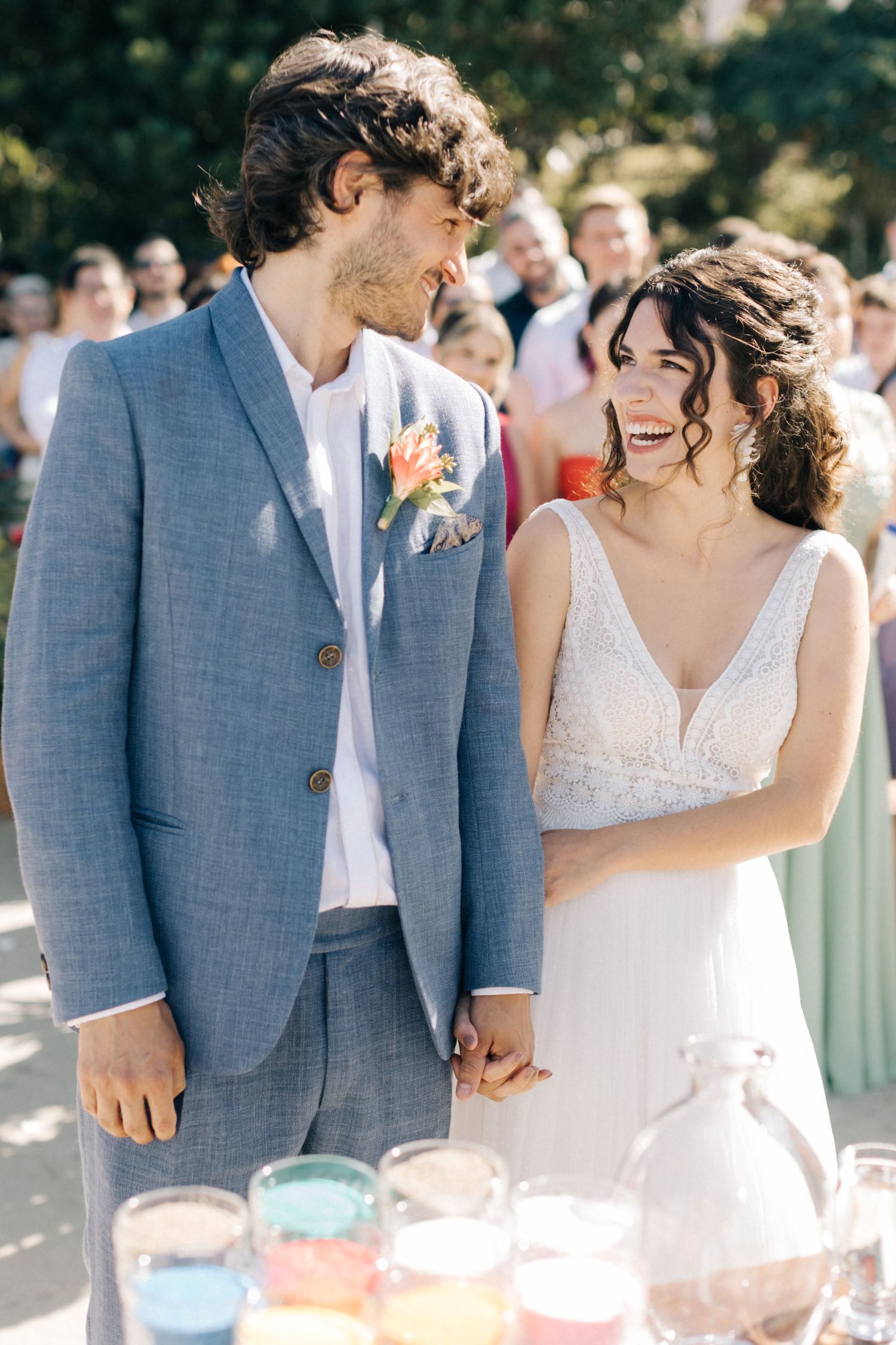 A couple shares a joyful moment together at their beach wedding, with the bride in white and groom in light blue.