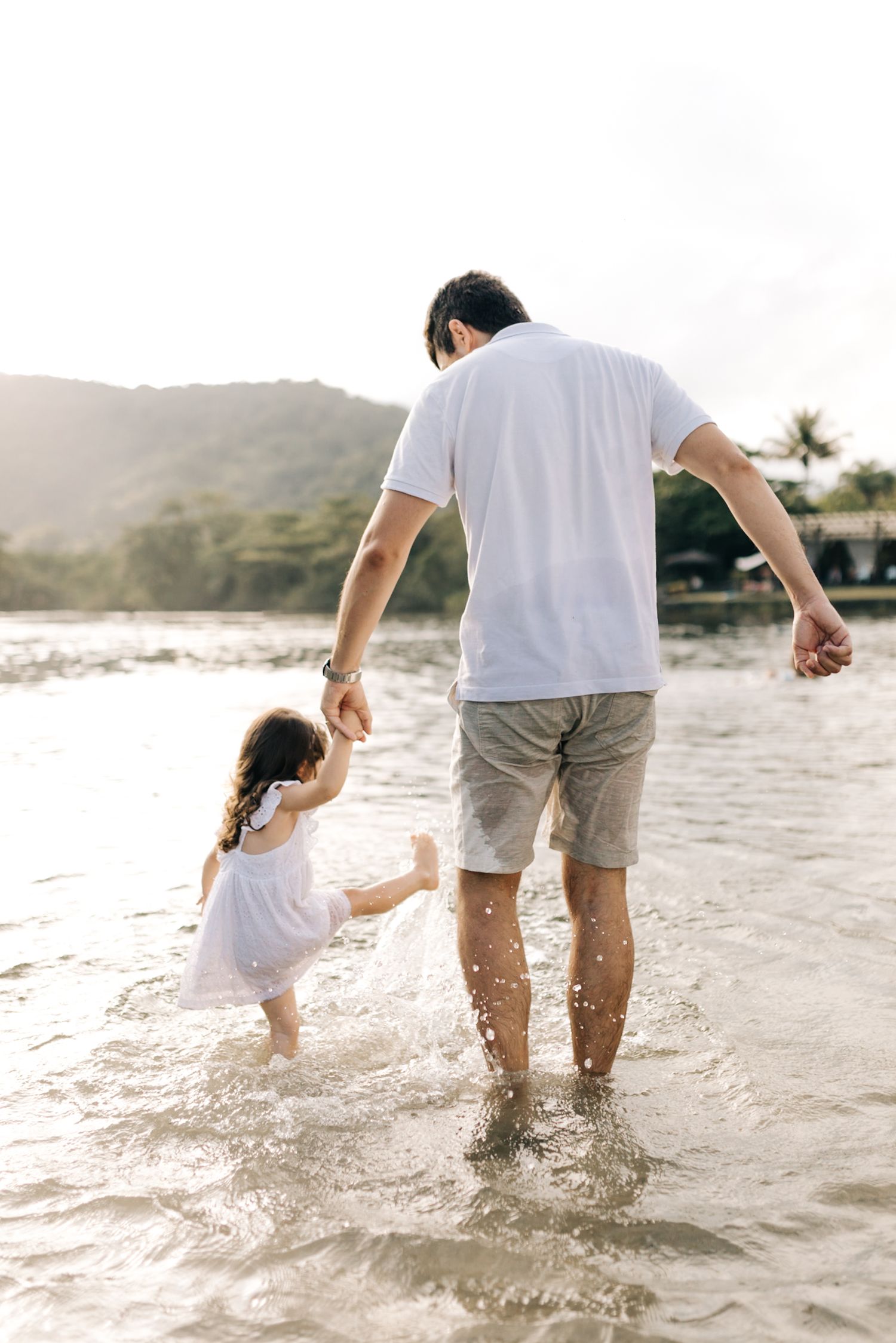 A tender moment between parent and child splashing in beach waves at sunset.