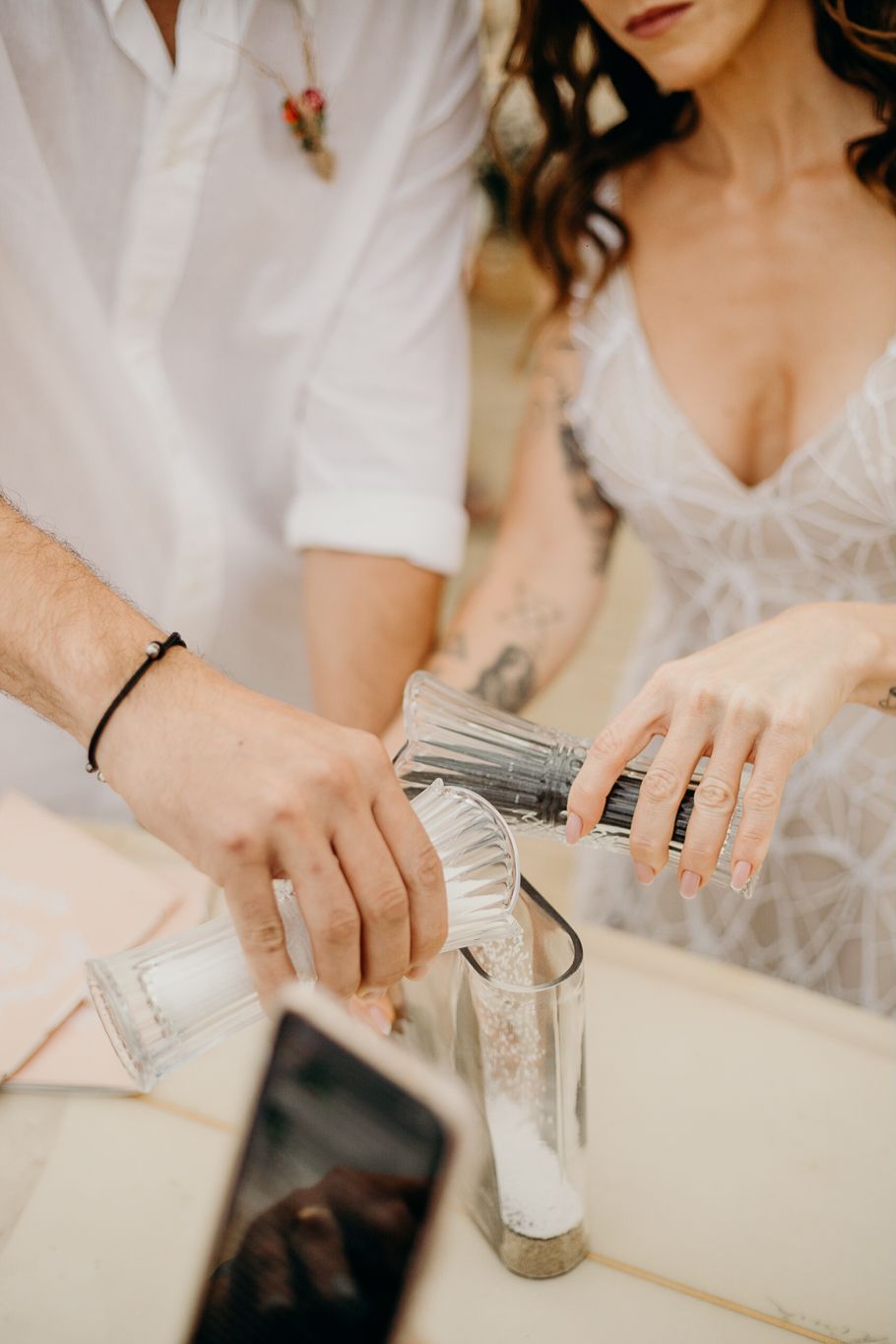 Close-up of hands pouring drinks into glasses during a wedding celebration.