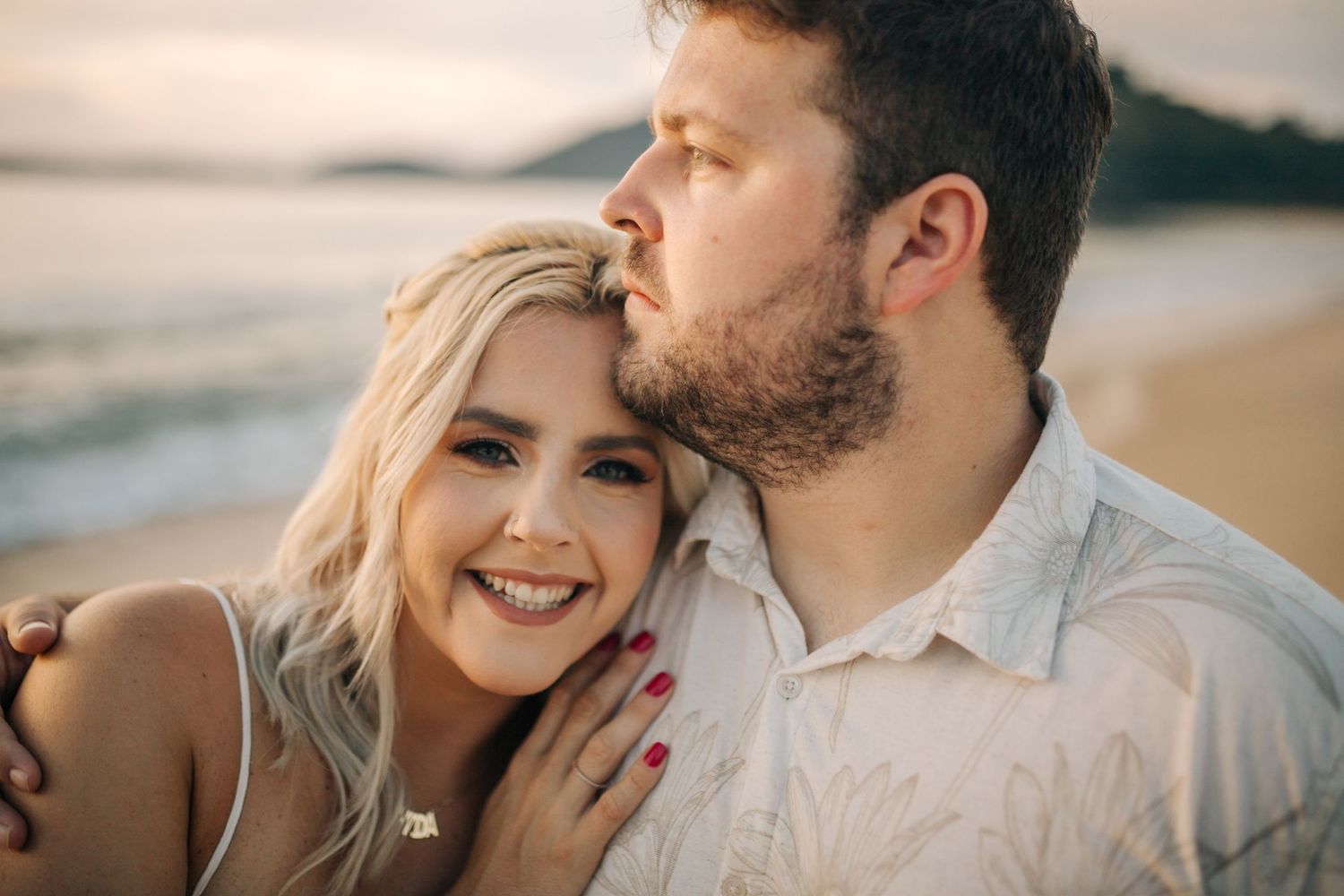 A tender moment between two people during a beach photoshoot at sunset.