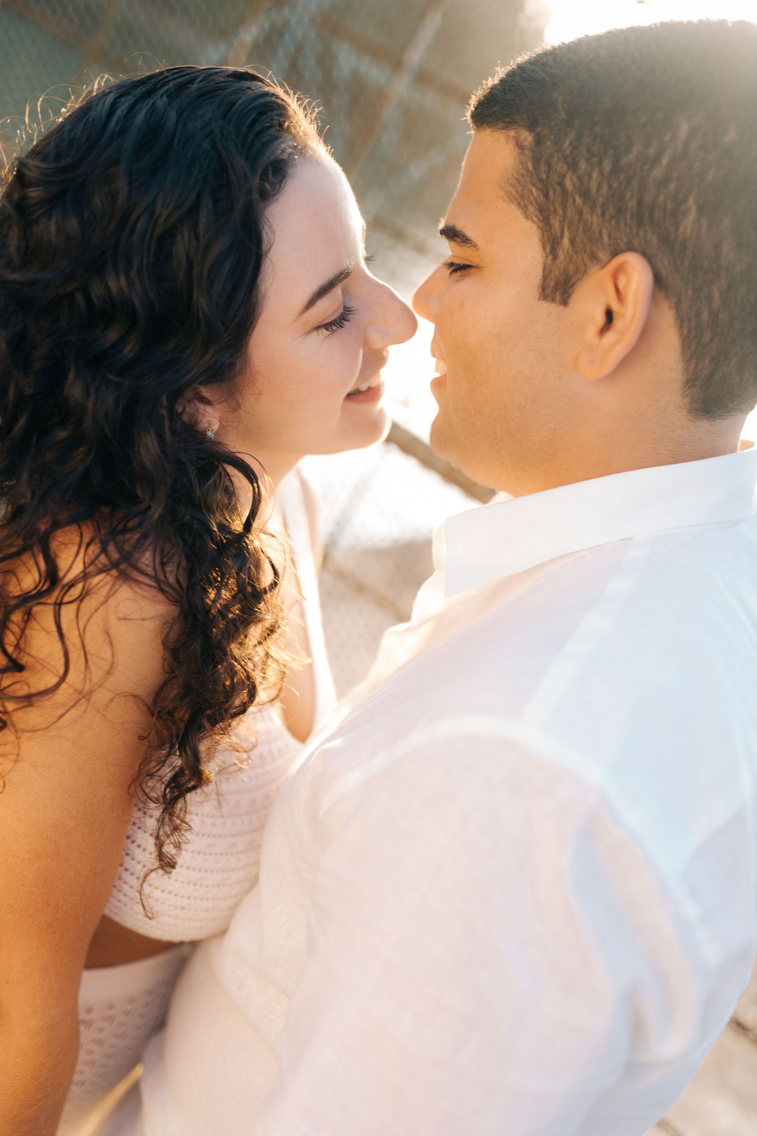 Close-up of couple about to kiss with sunlight streaming through geometric pattern background.