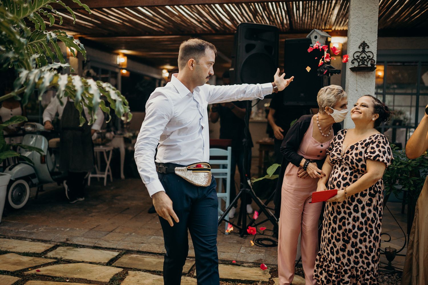Guests celebrate at outdoor venue under wooden pergola with ambient lighting.