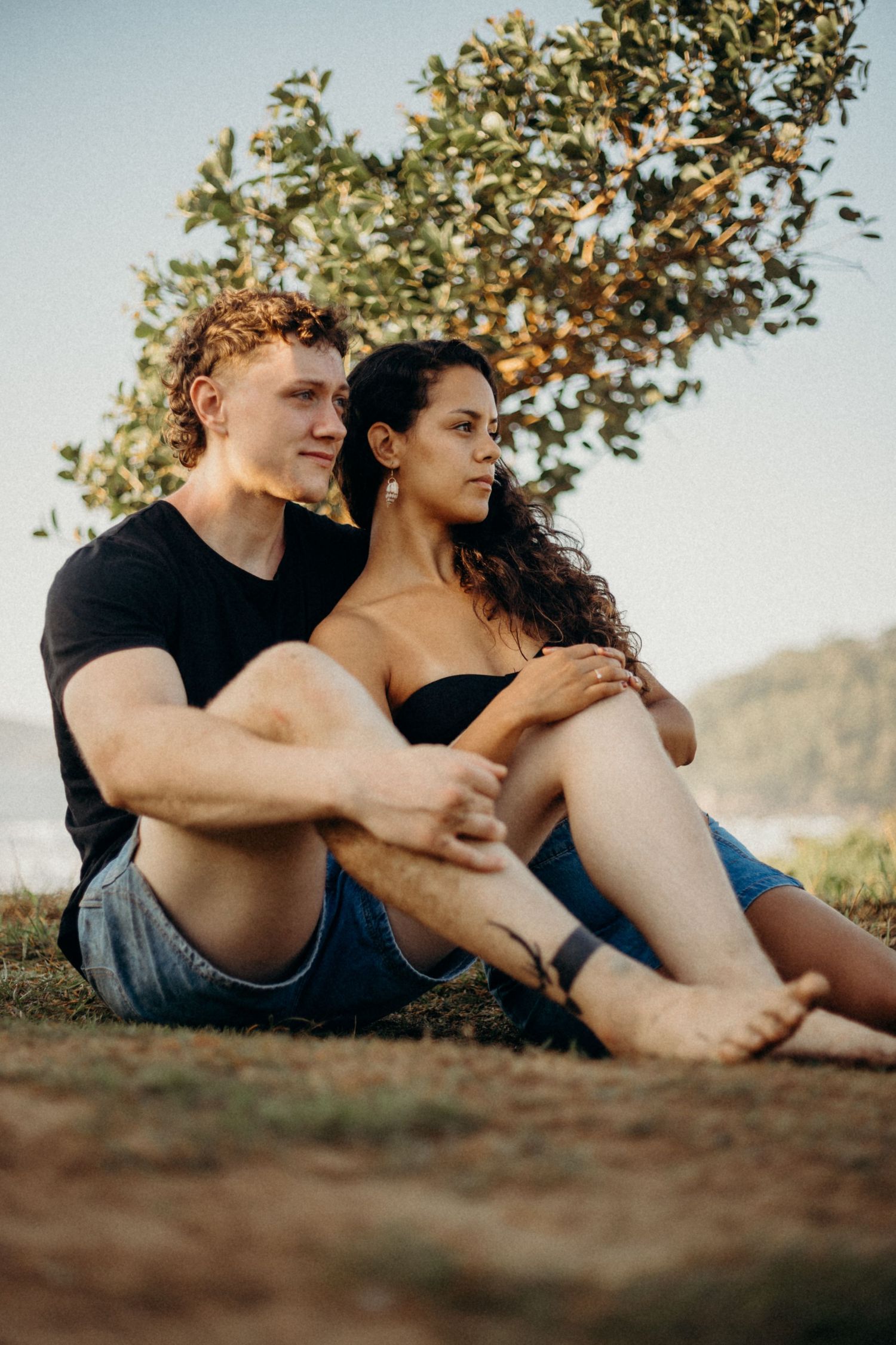 Couple relaxing together on grassy overlook with ocean view in background.
