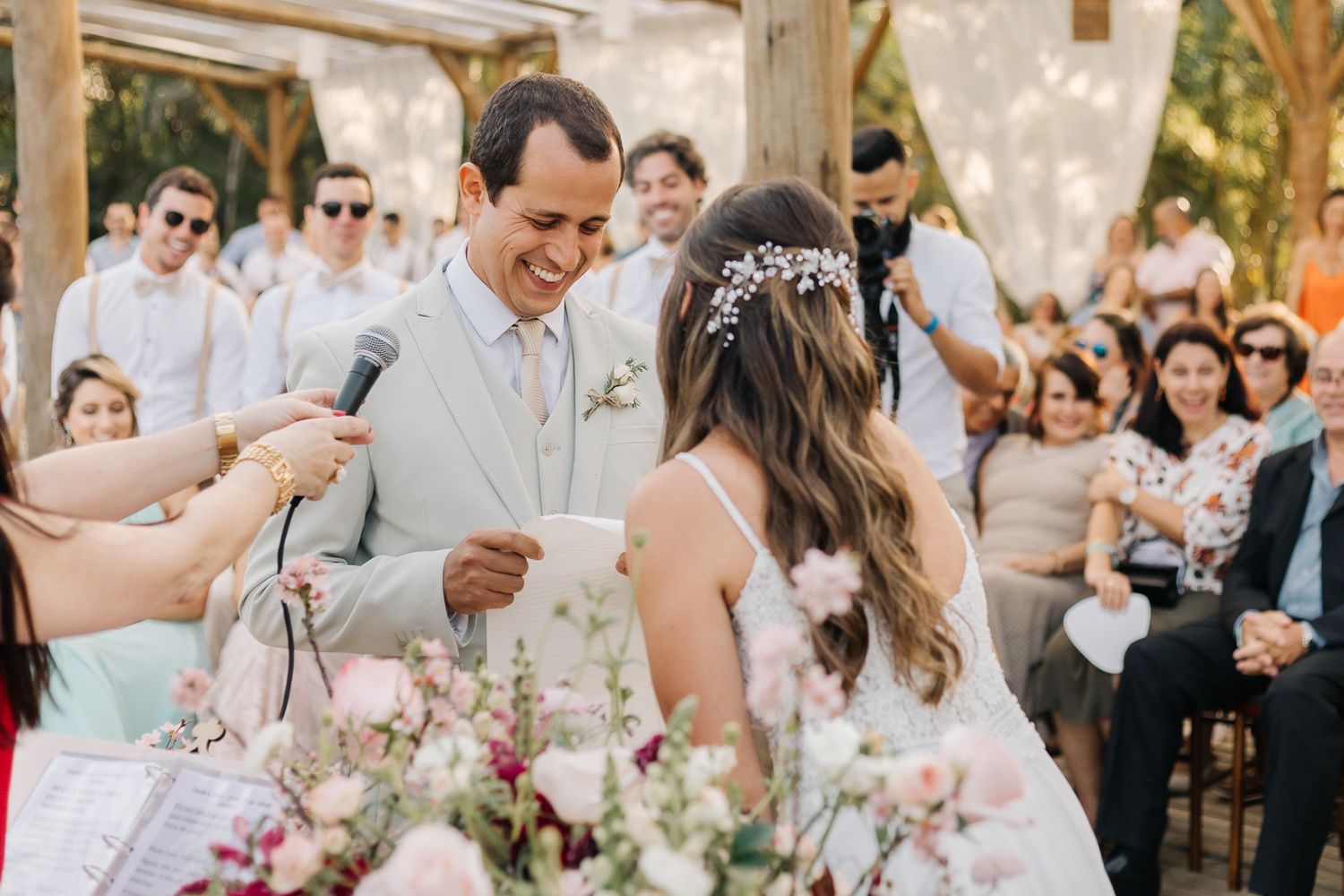 Outdoor wedding scene with wooden beams and pink floral decorations.