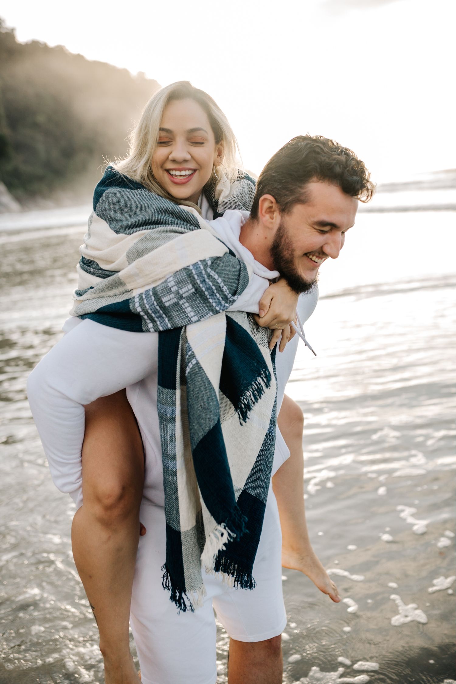 Playful beach photography showing couple's natural joy during piggyback moment.