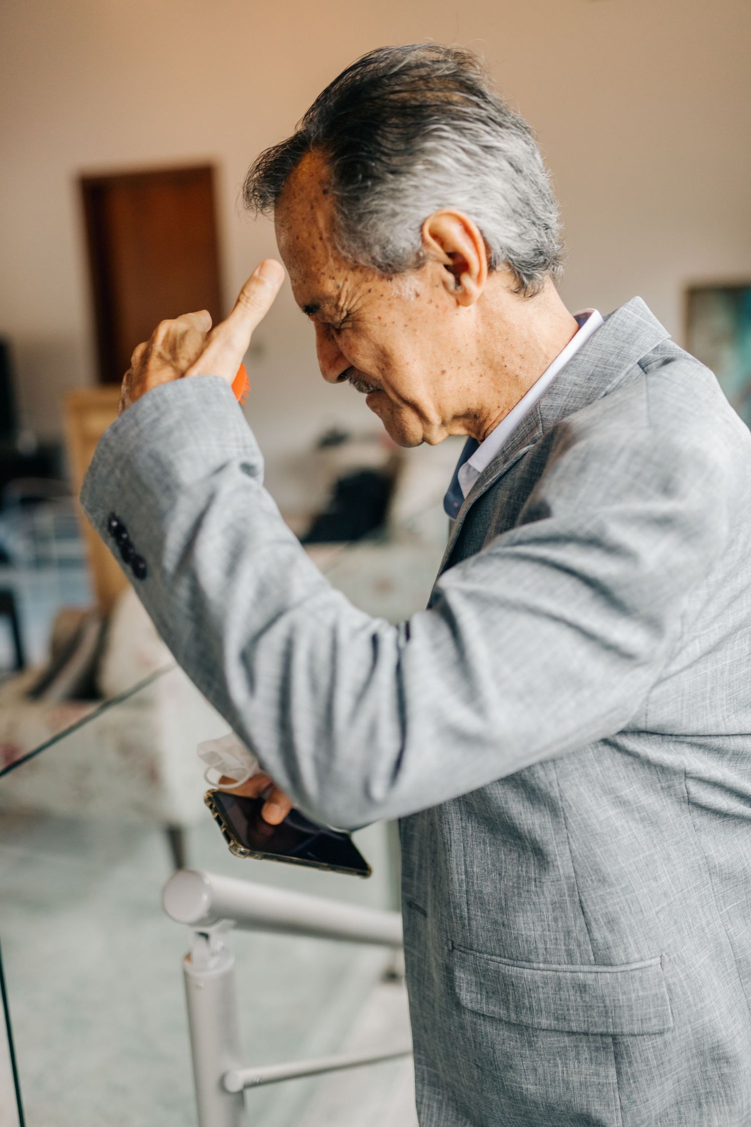 An emotional moment as a man in a grey suit wipes his eyes while holding a phone.