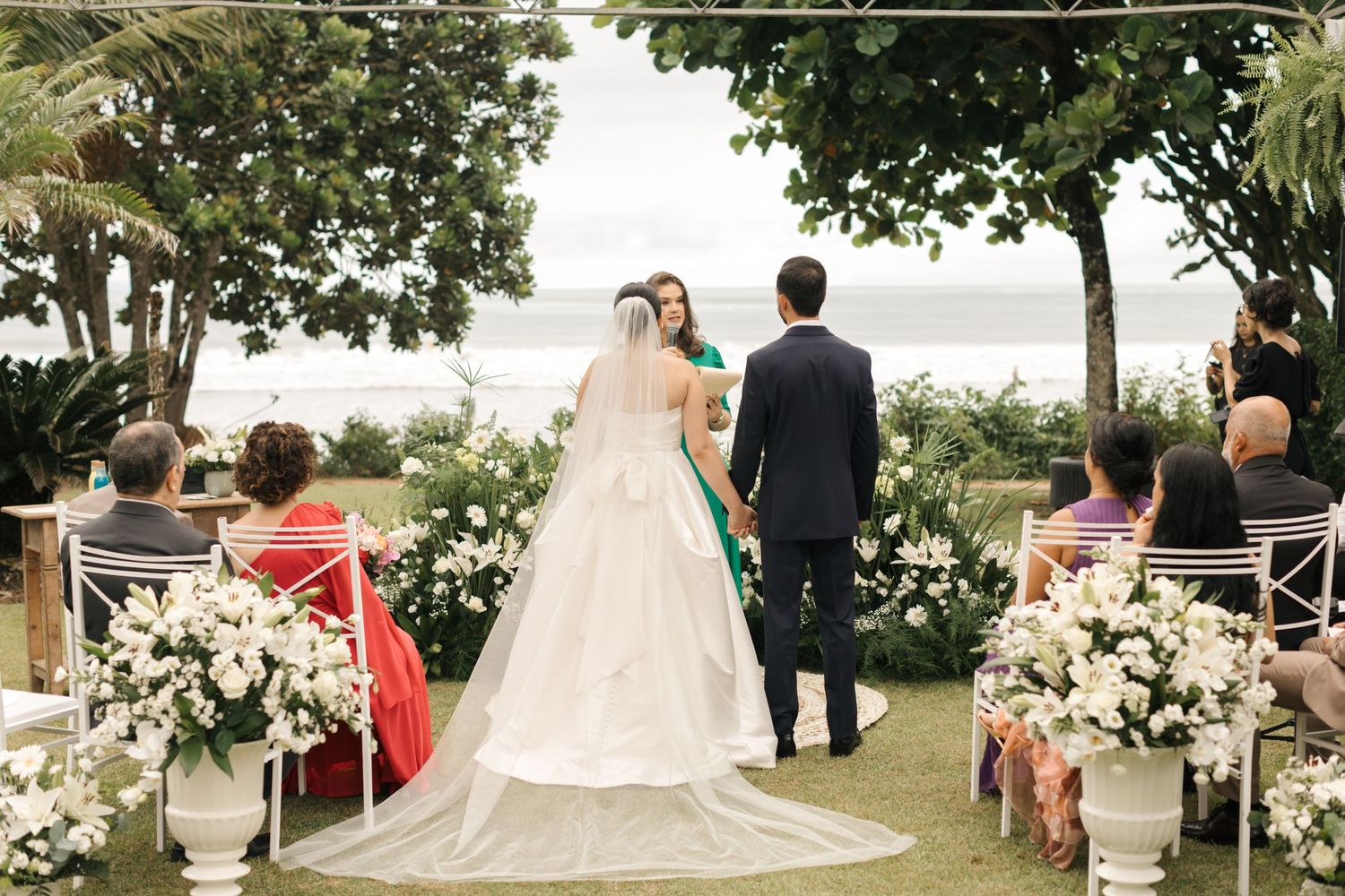 Panoramic view of an outdoor wedding ceremony with white floral arrangements and natural scenery.