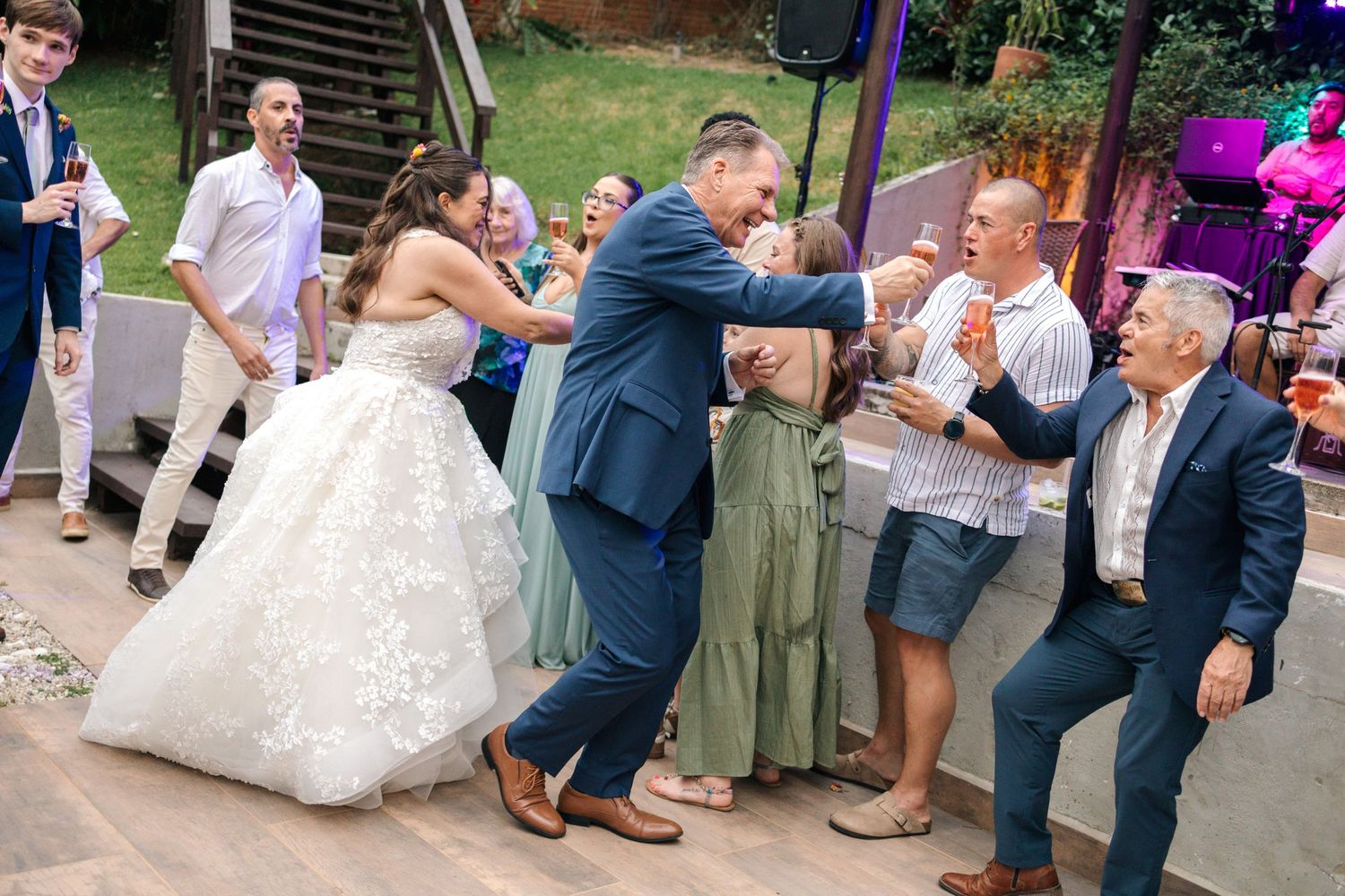 Wedding reception guests dancing and celebrating on outdoor patio.