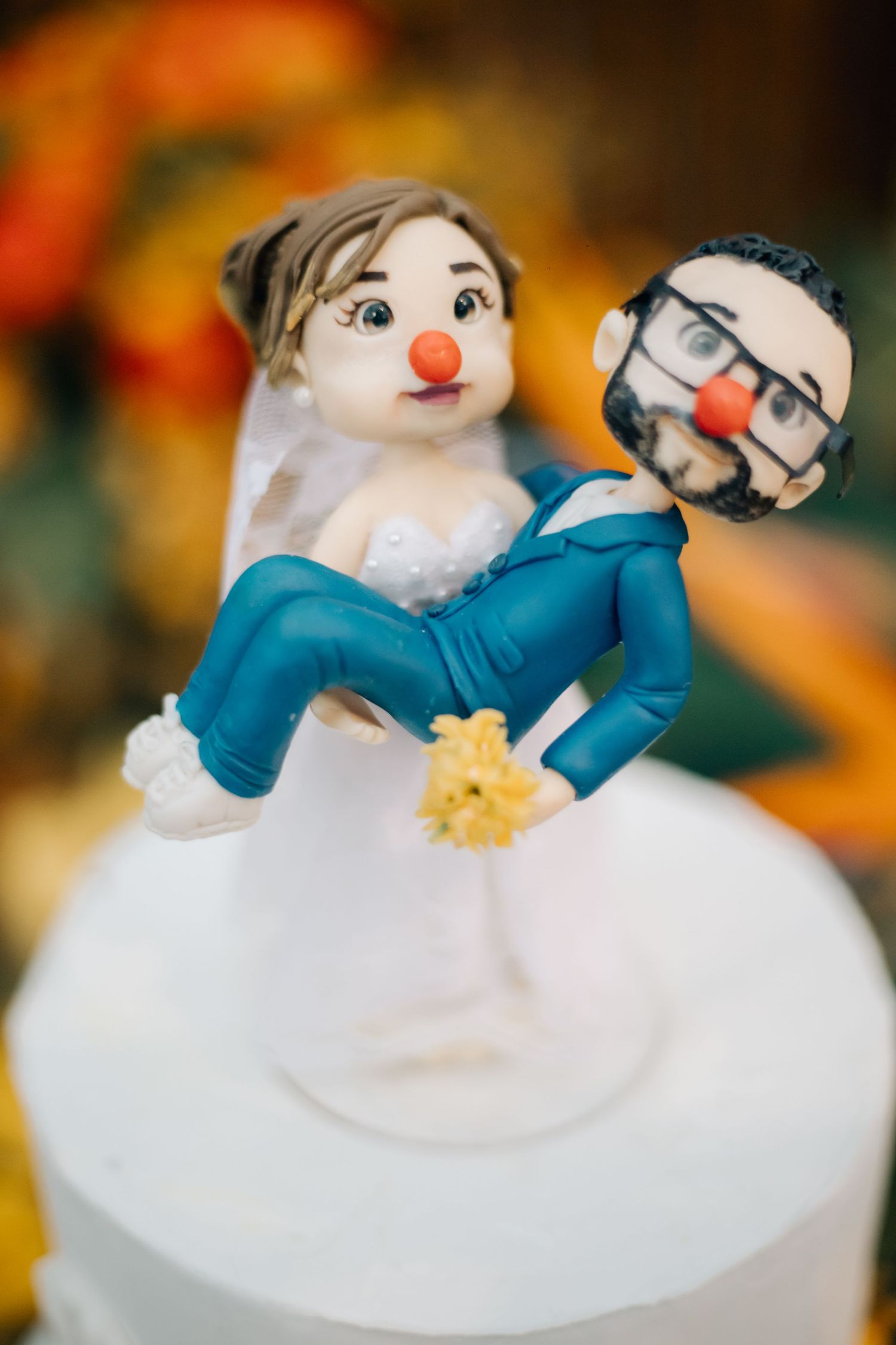 Whimsical wedding cake topper featuring a playful pose with two figures decorated in blue and white.