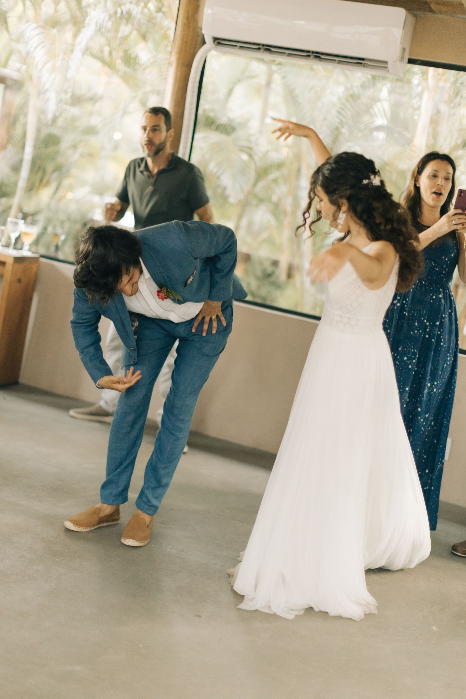 Wedding guests dance on a reception floor, with a bride in white and guests in sparkly attire.