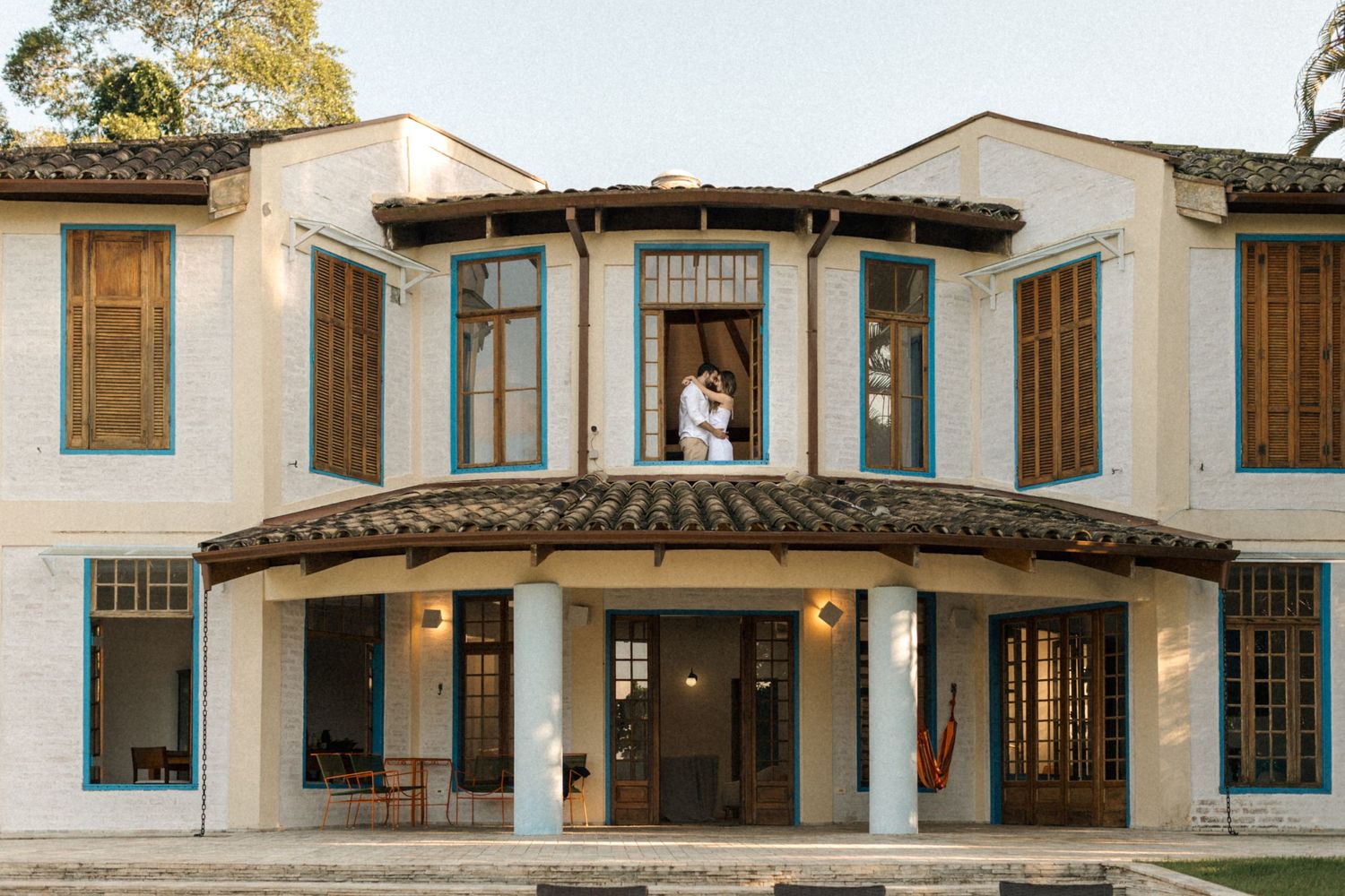 Luxurious villa with Spanish colonial architecture and curved balcony overlooks a pristine pool.