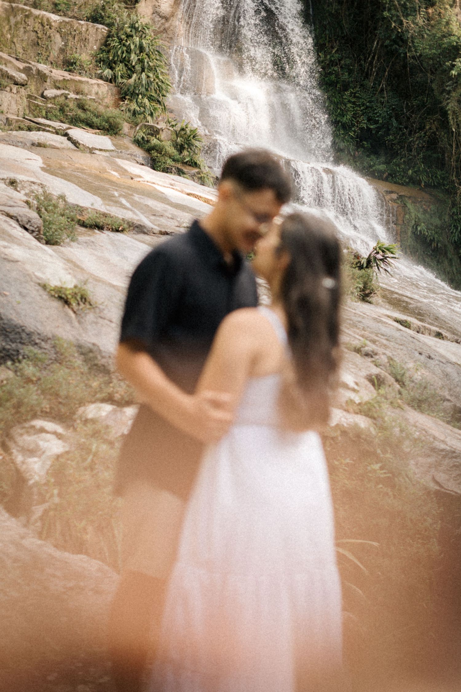 Progressive shots of a romantic encounter near a misty waterfall in nature.