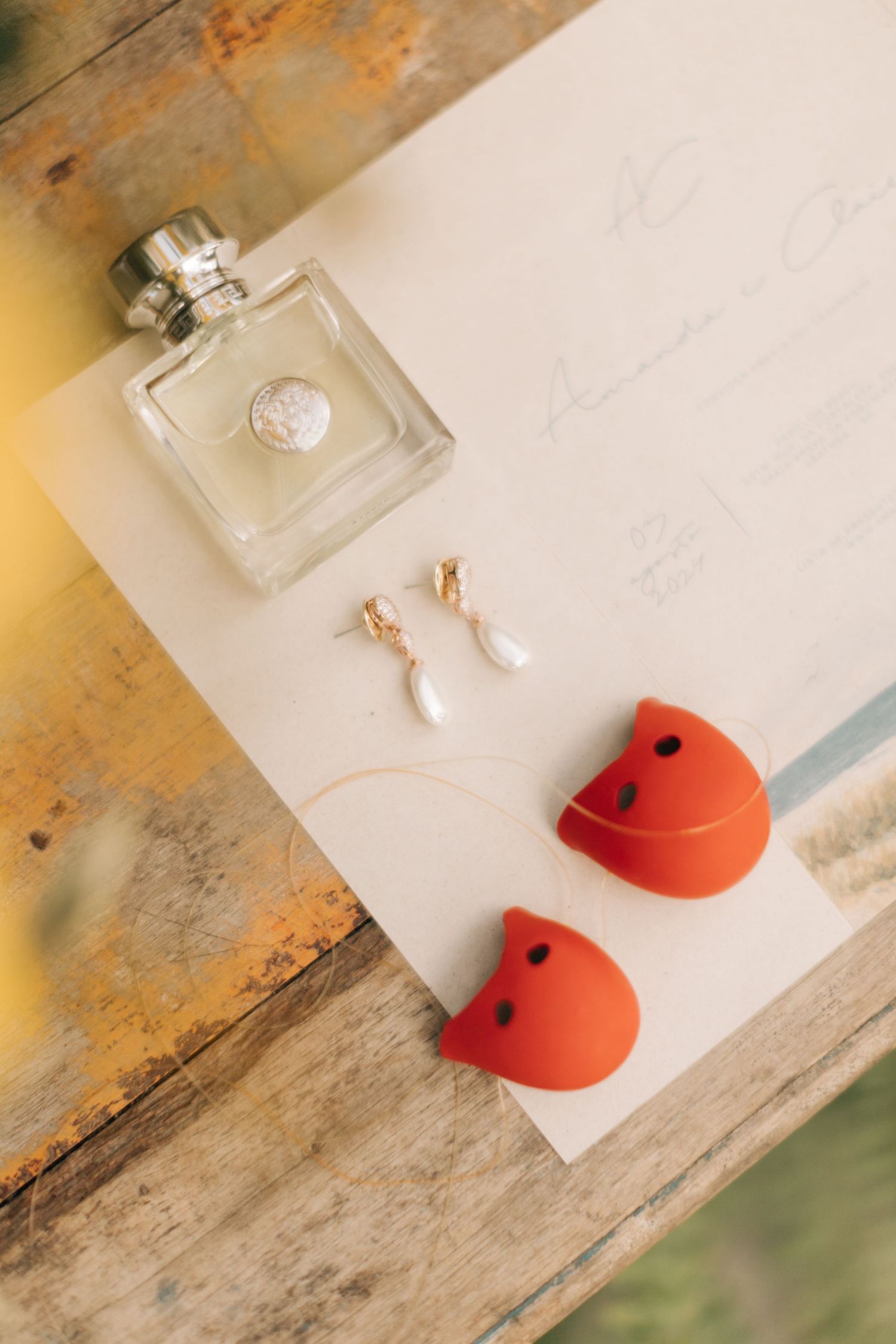 Wedding accessories including perfume, pearl earrings and red heart-shaped decorations on white paper.