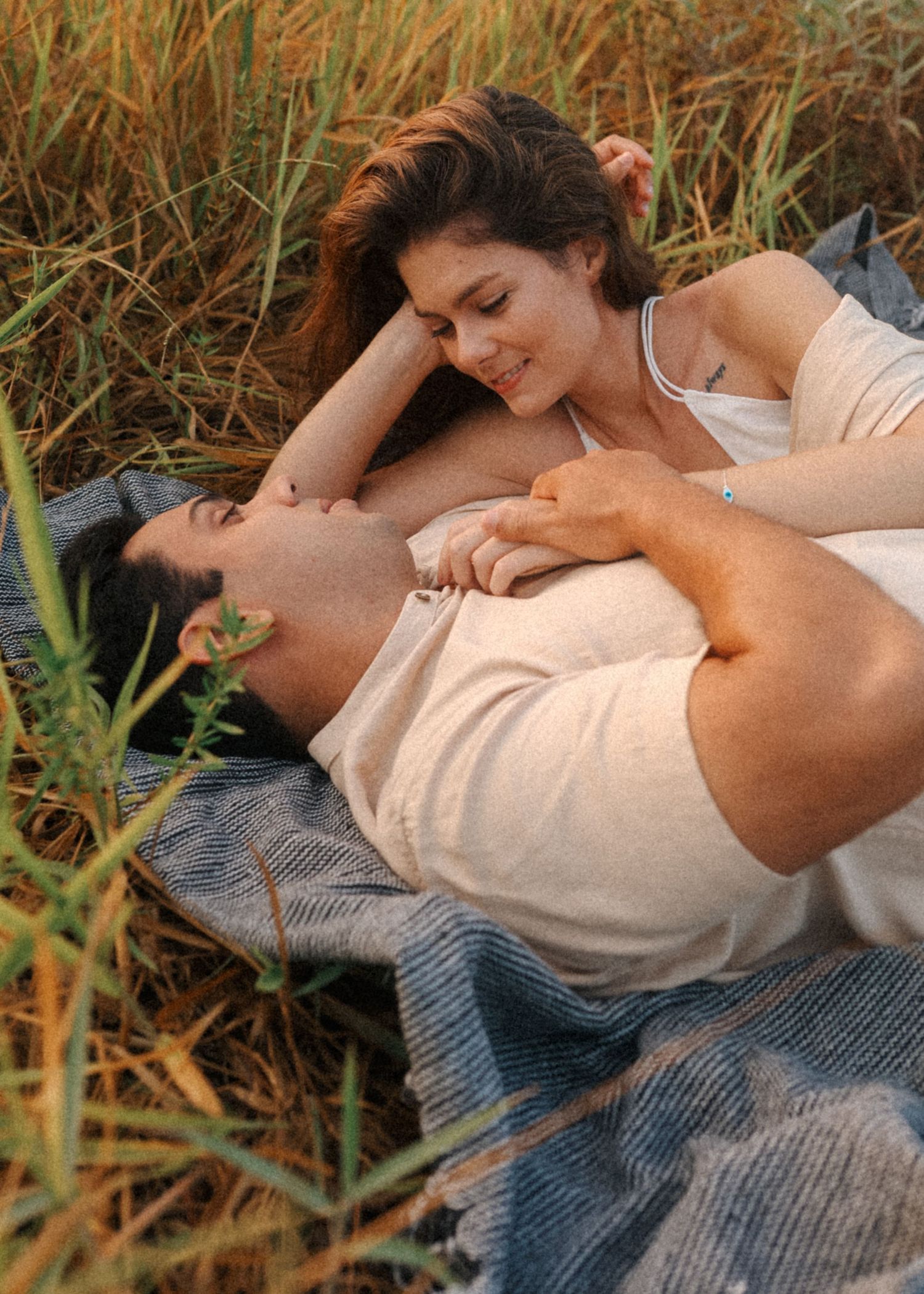 Candid moments captured of a couple relaxing on a blanket in nature.