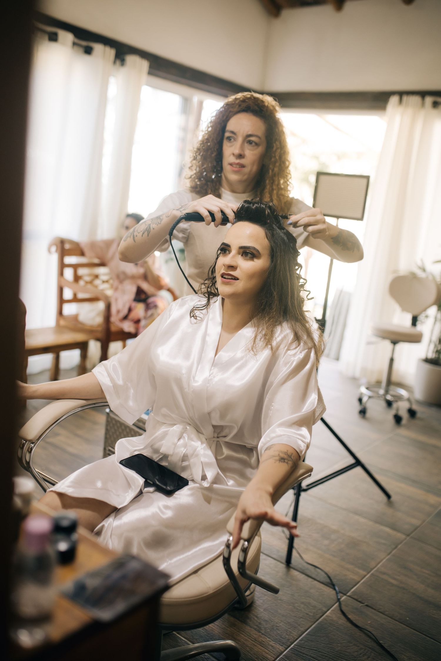 Hair styling session in progress at bridal preparation room with natural lighting.