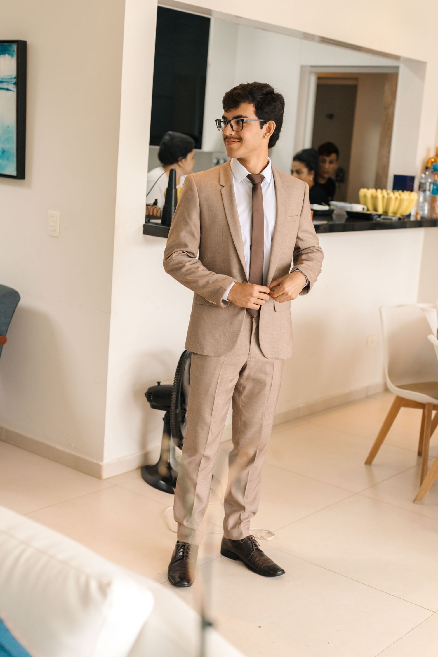 Person in a beige suit poses in a bright modern interior space.