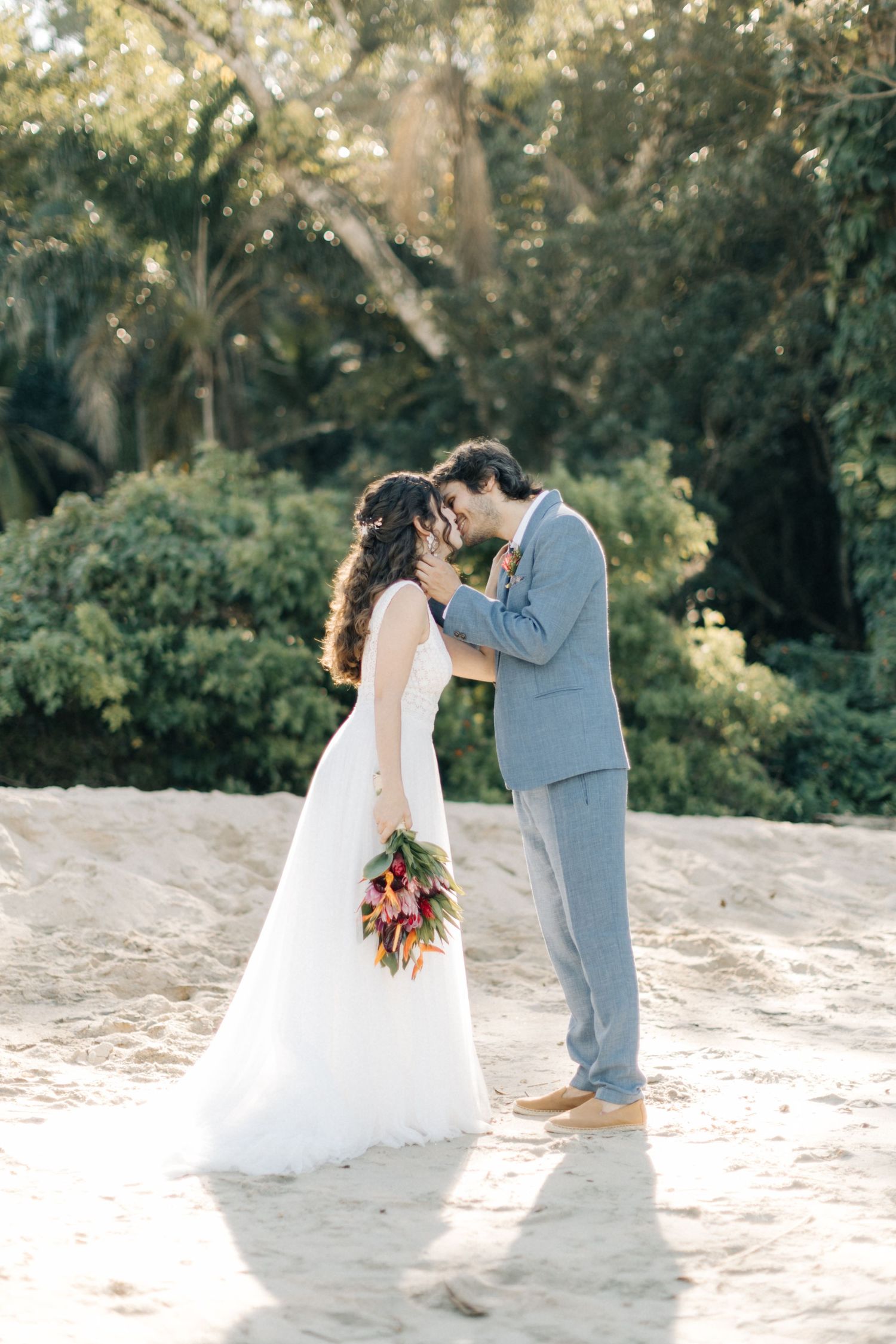 A couple shares their first dance on a sandy beach during their wedding.