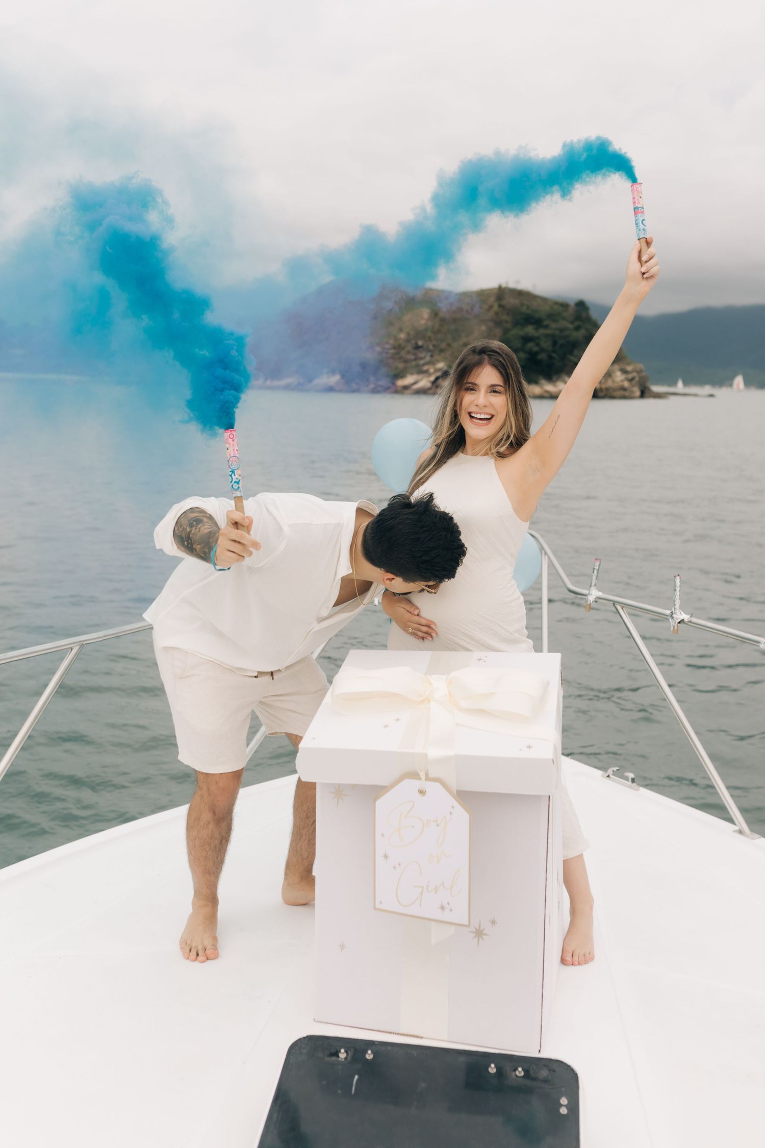 Celebratory moment on boat deck with blue smoke flares against mountain backdrop.