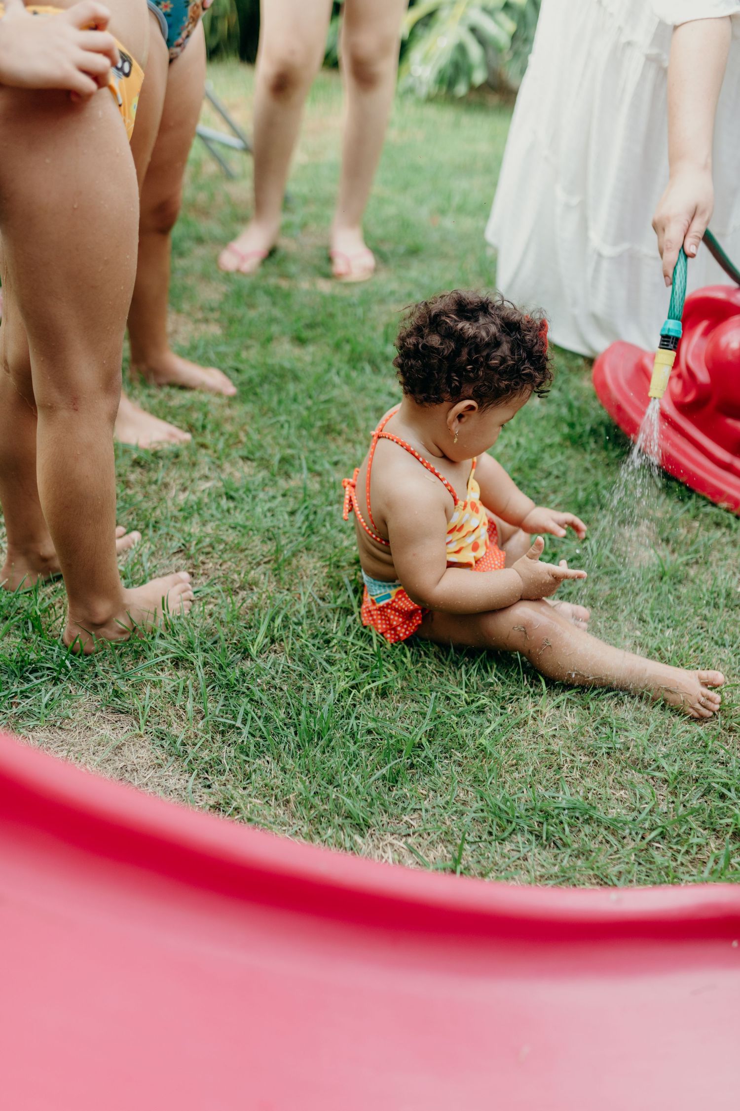 Little legs and feet visible around a pink inflatable pool during outdoor summer play.