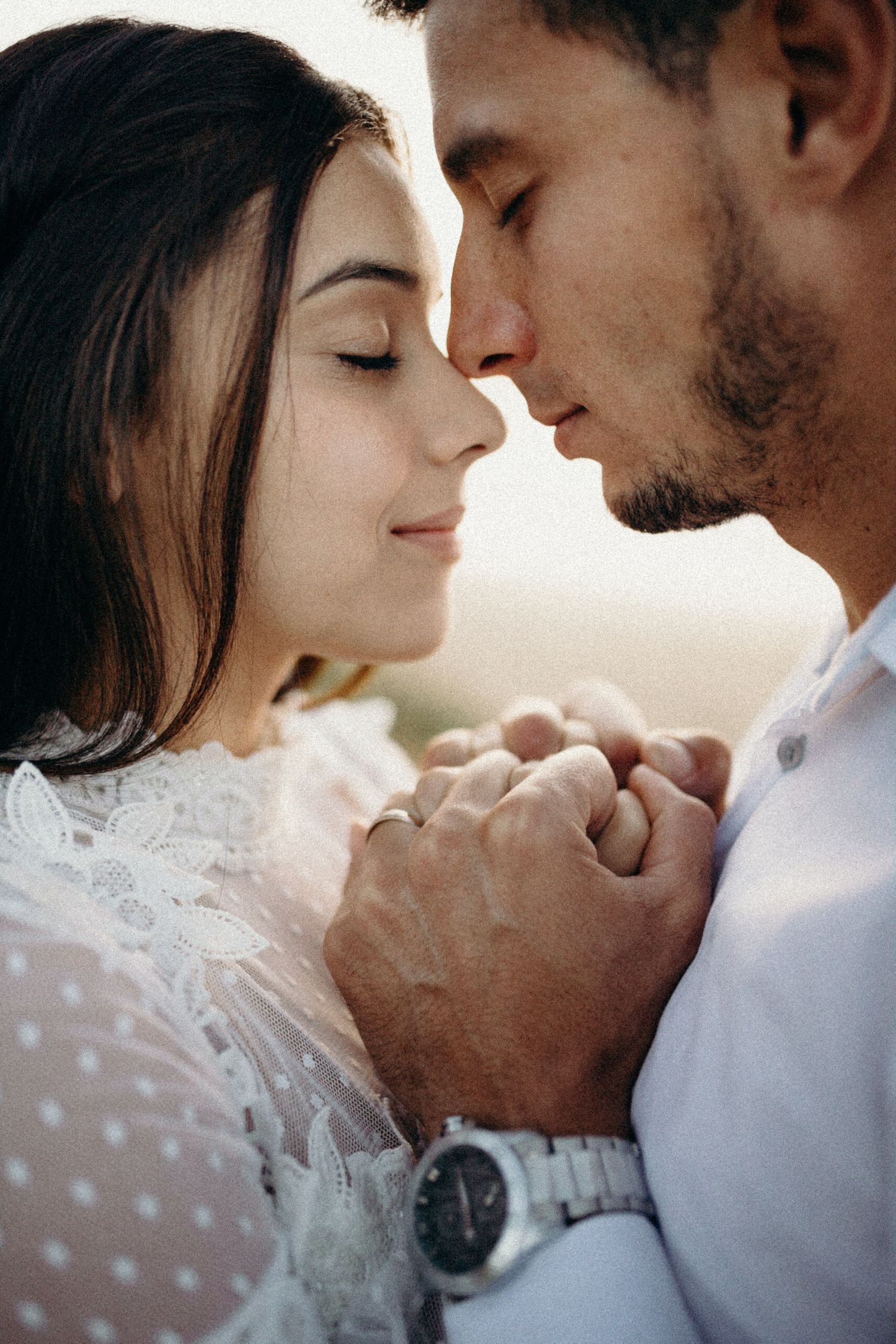 Intimate portrait of couple in white attire sharing loving moment.