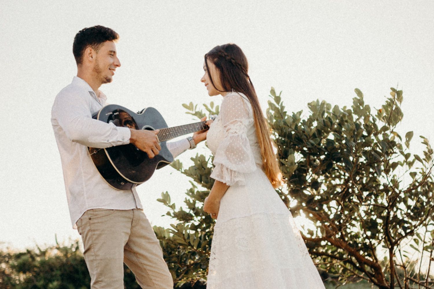 Couple plays music together during outdoor wedding photo session.