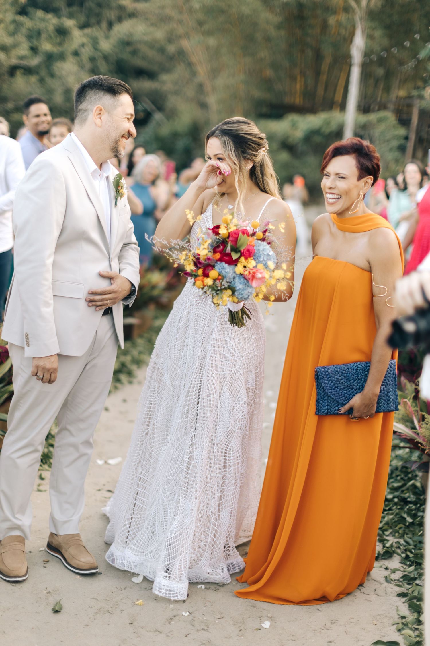 Candid moment of laughter during wedding celebration with white and orange attire.