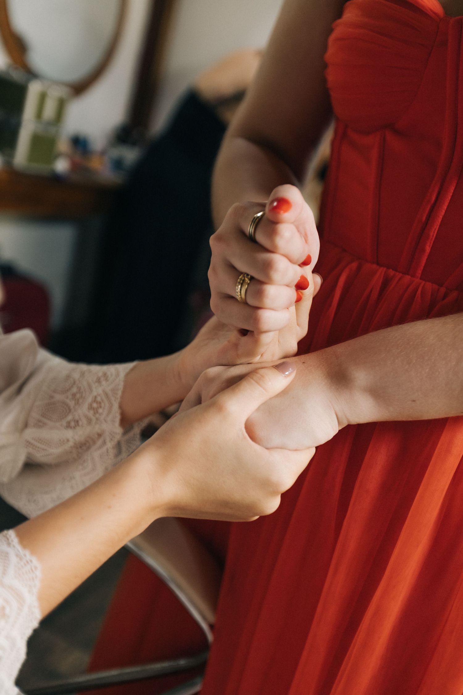 Close-up of hands clasping together, with one person wearing a red dress.