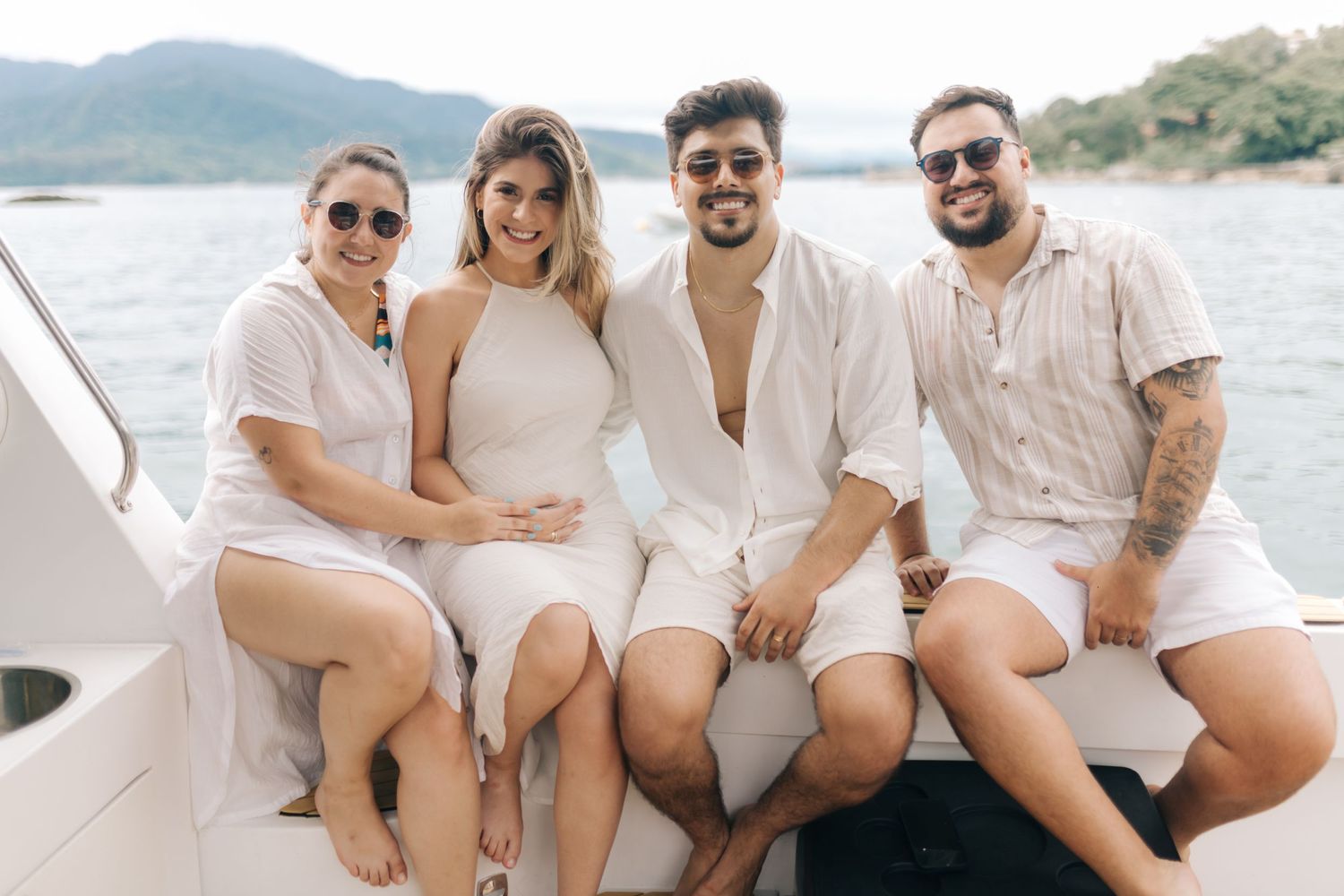 Group in coordinated white outfits relaxing on boat with mountains in background.