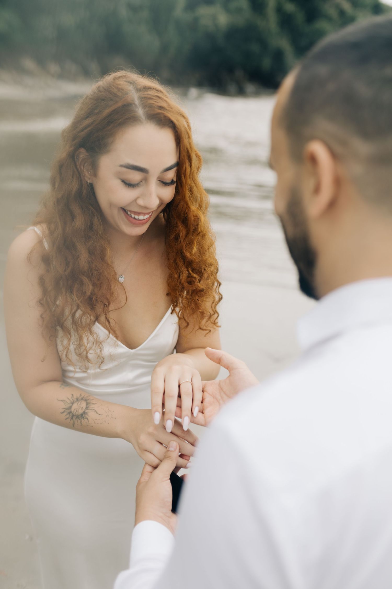 A couple admires a ring together during a romantic beach proposal moment.