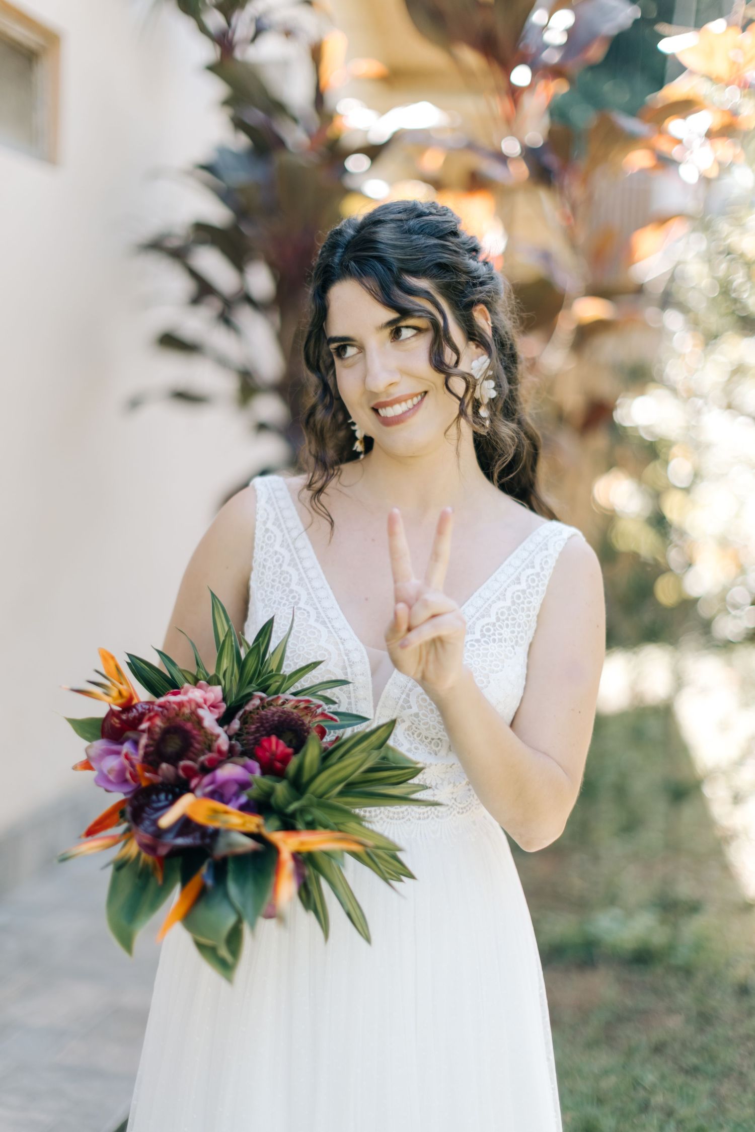 A joyful moment captured in a garden with a tropical bouquet and peace sign gesture.